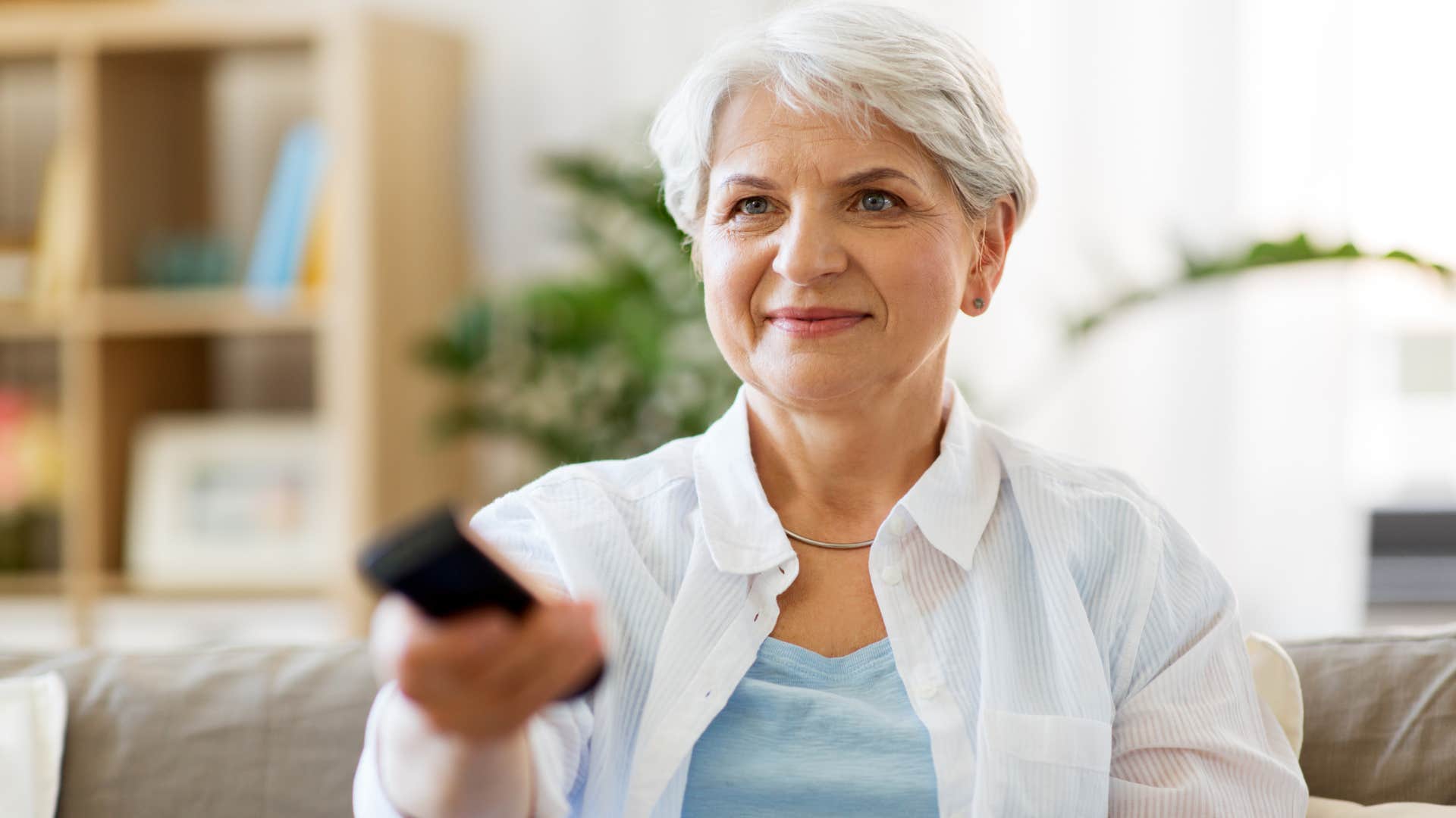 woman scrolling through streaming services with remote