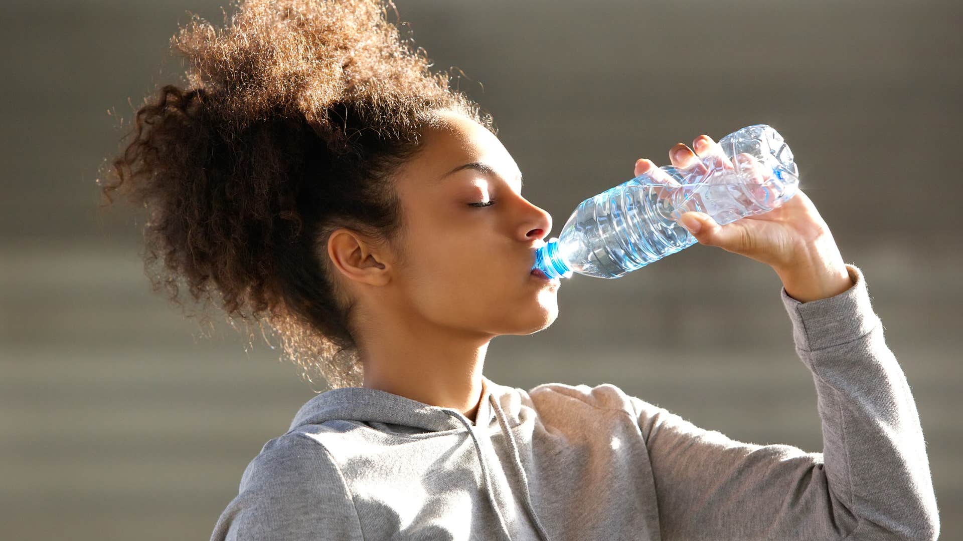 woman drinking bottled water outside