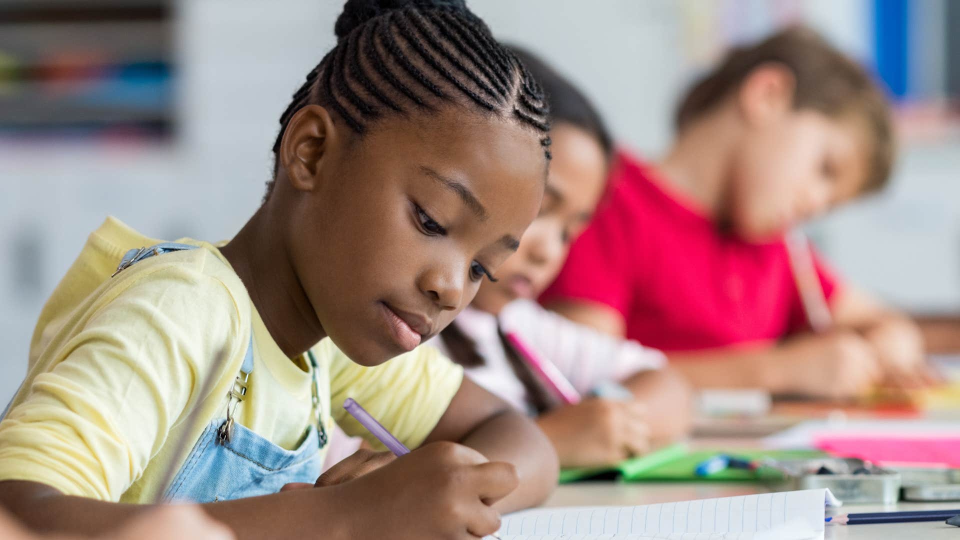 little girl who doesn't brag doing work in a classroom