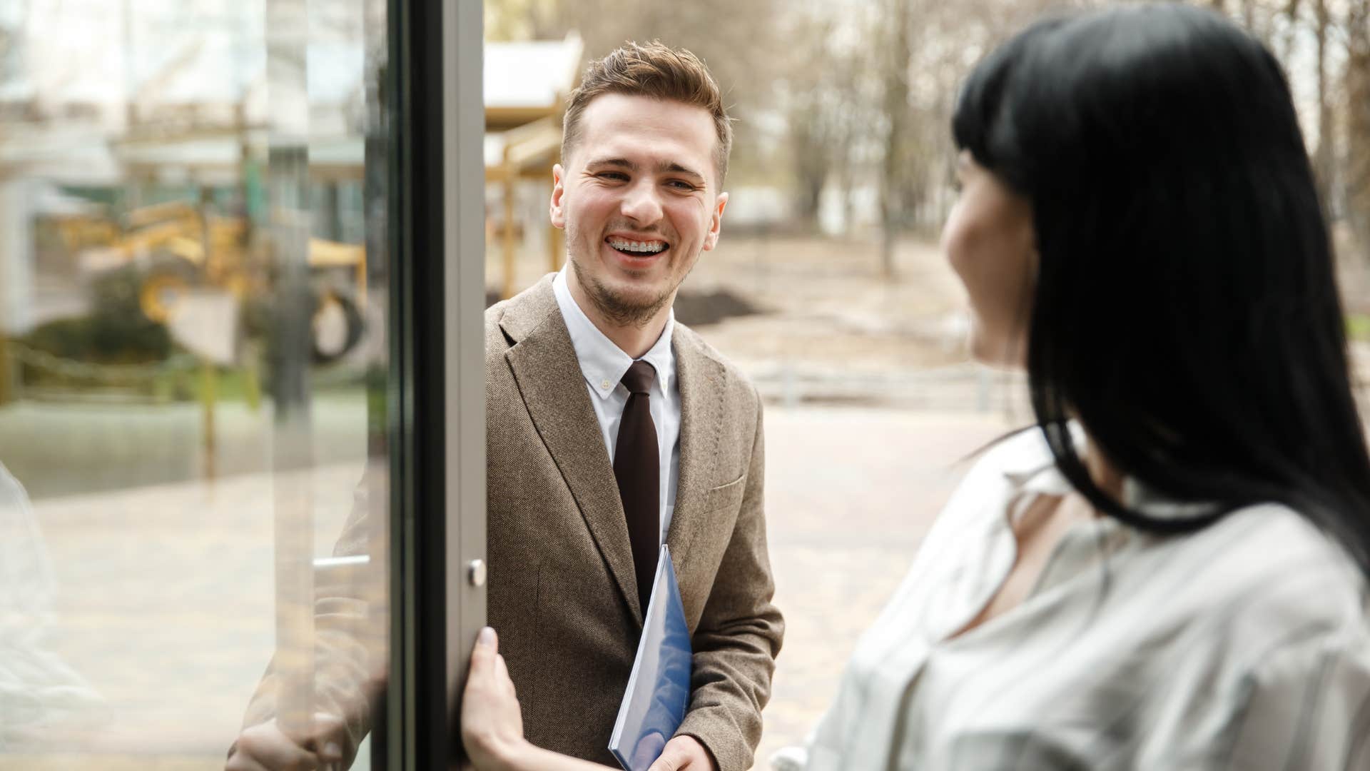 man politely holding the door for a woman