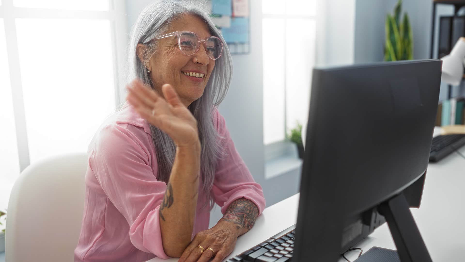 authentic woman smiling and waving at her laptop