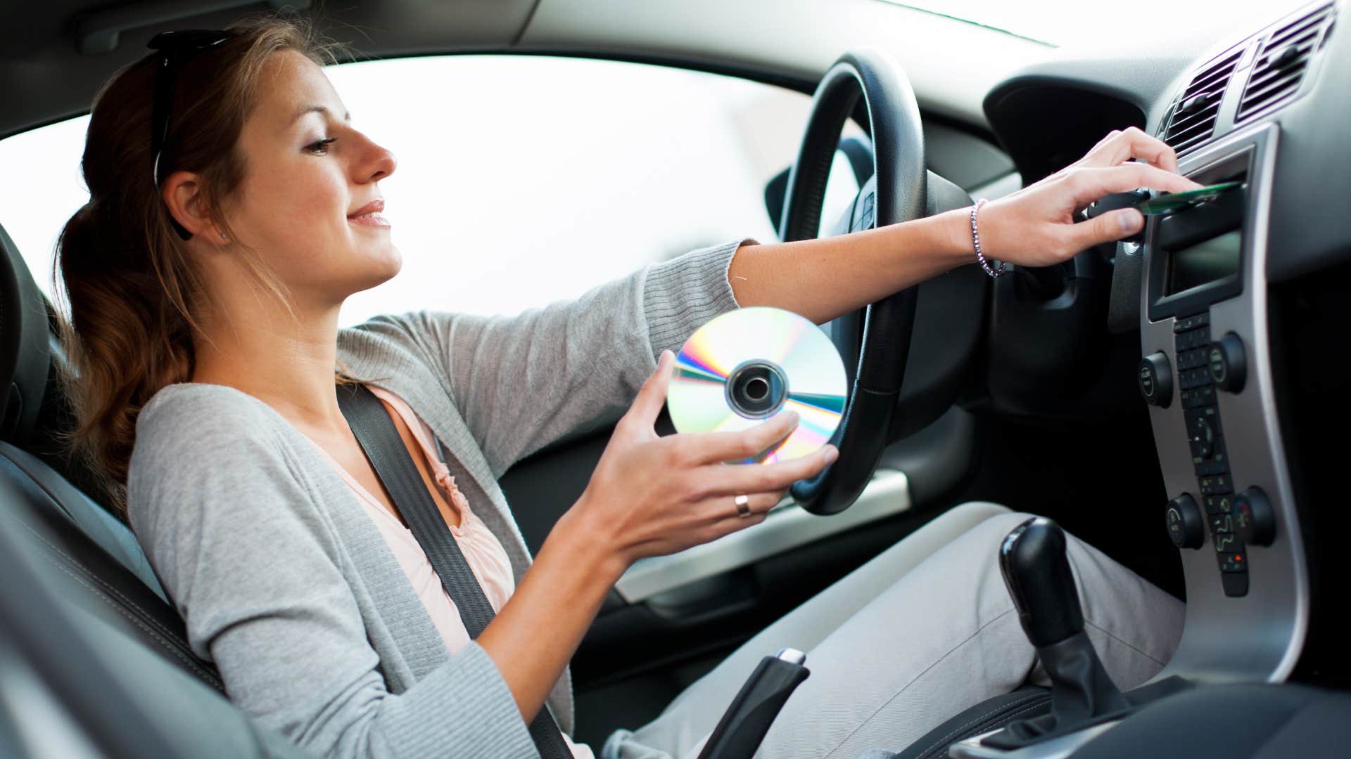 a woman listens to her old cds in her car