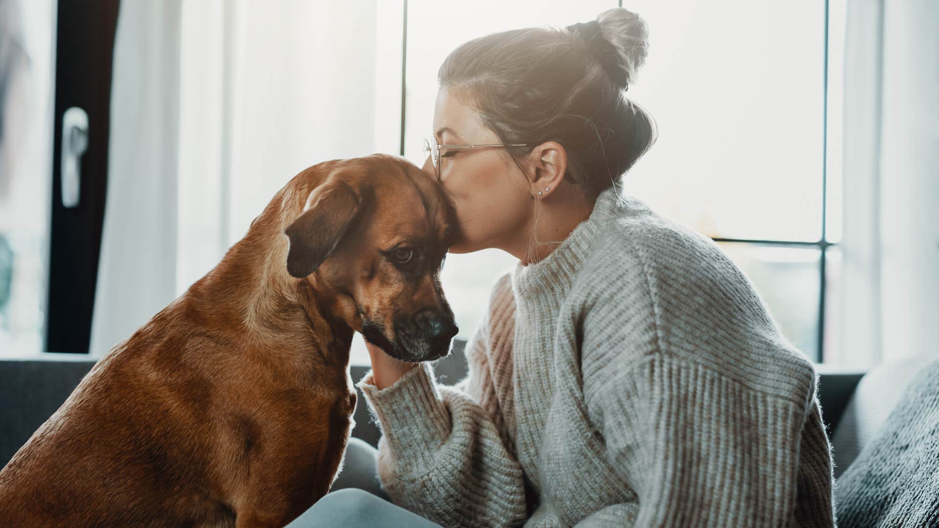 a woman gives affection to her dog that she takes care of