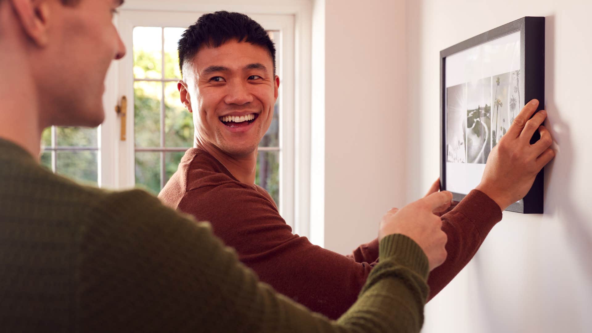 man being his authentic self hanging artwork with his partner