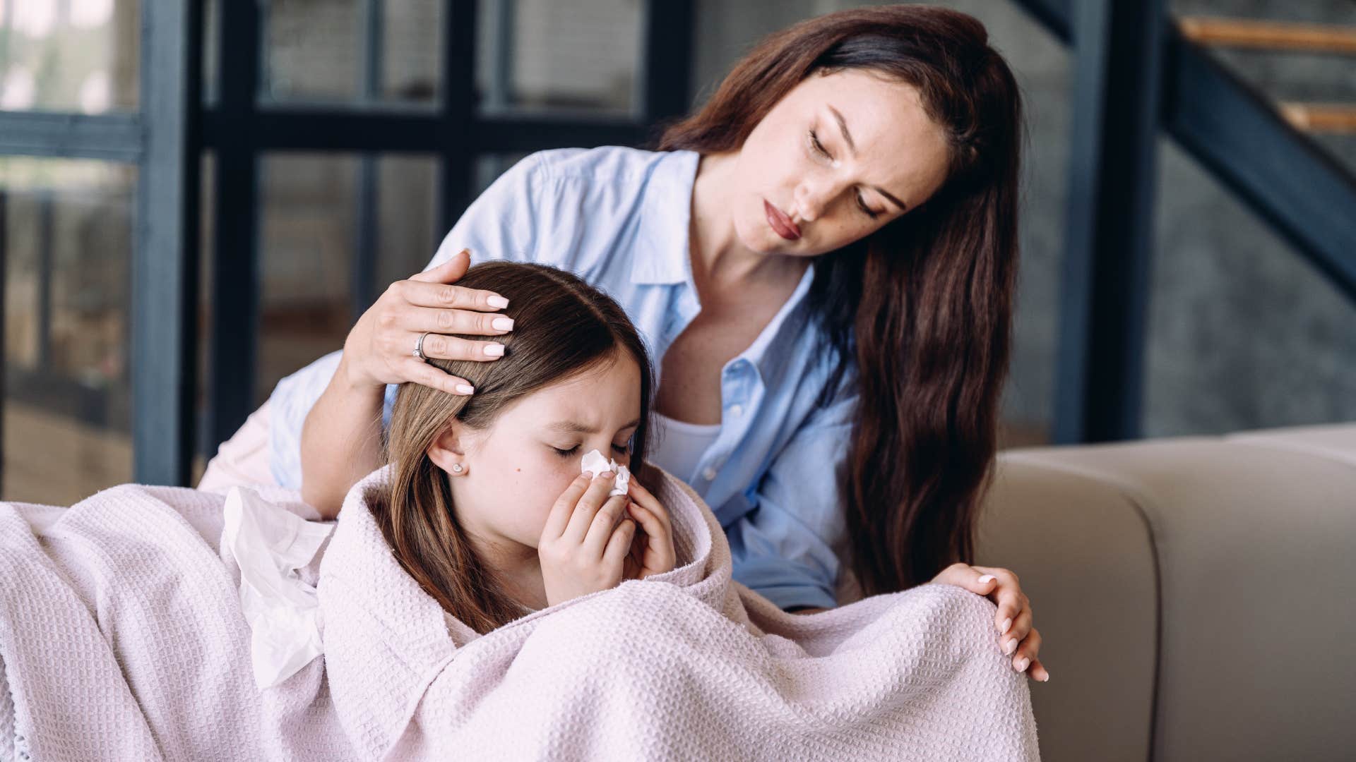 mother comforting her daughter snuggling her favorite blanket