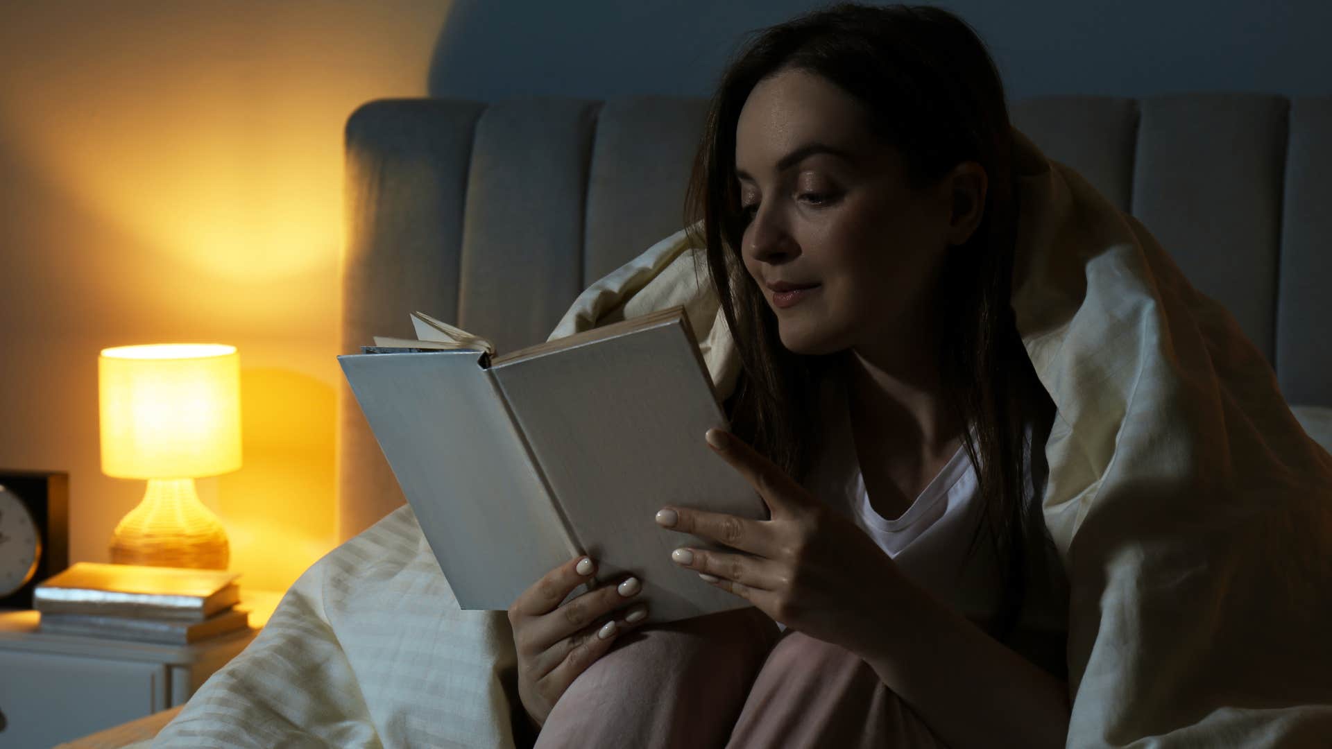 grown woman using a nightlight while reading in bed