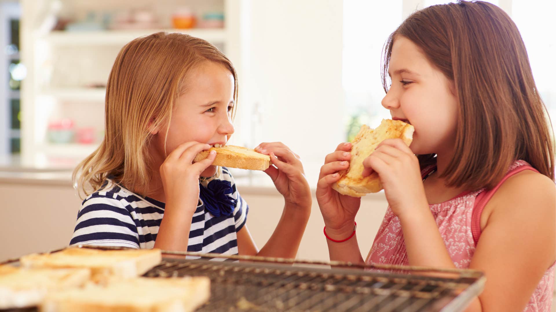 two young girls eating sandwiches after mother called them for dinner