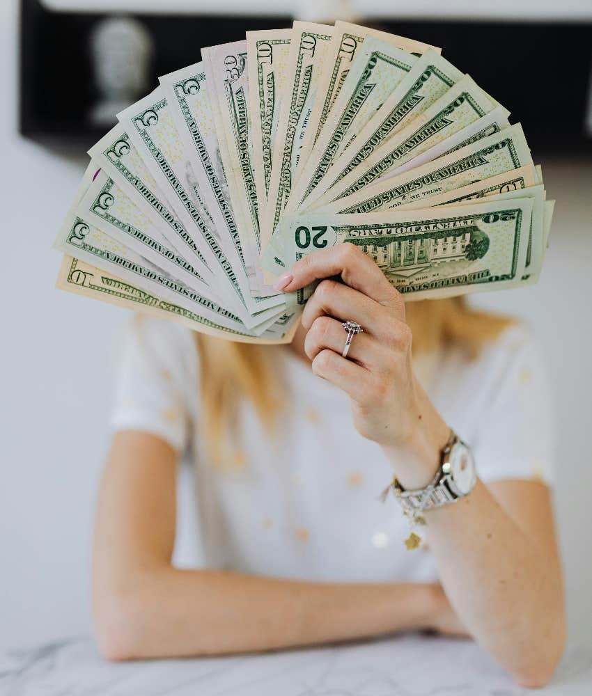 woman holding money fanned out in front of her face