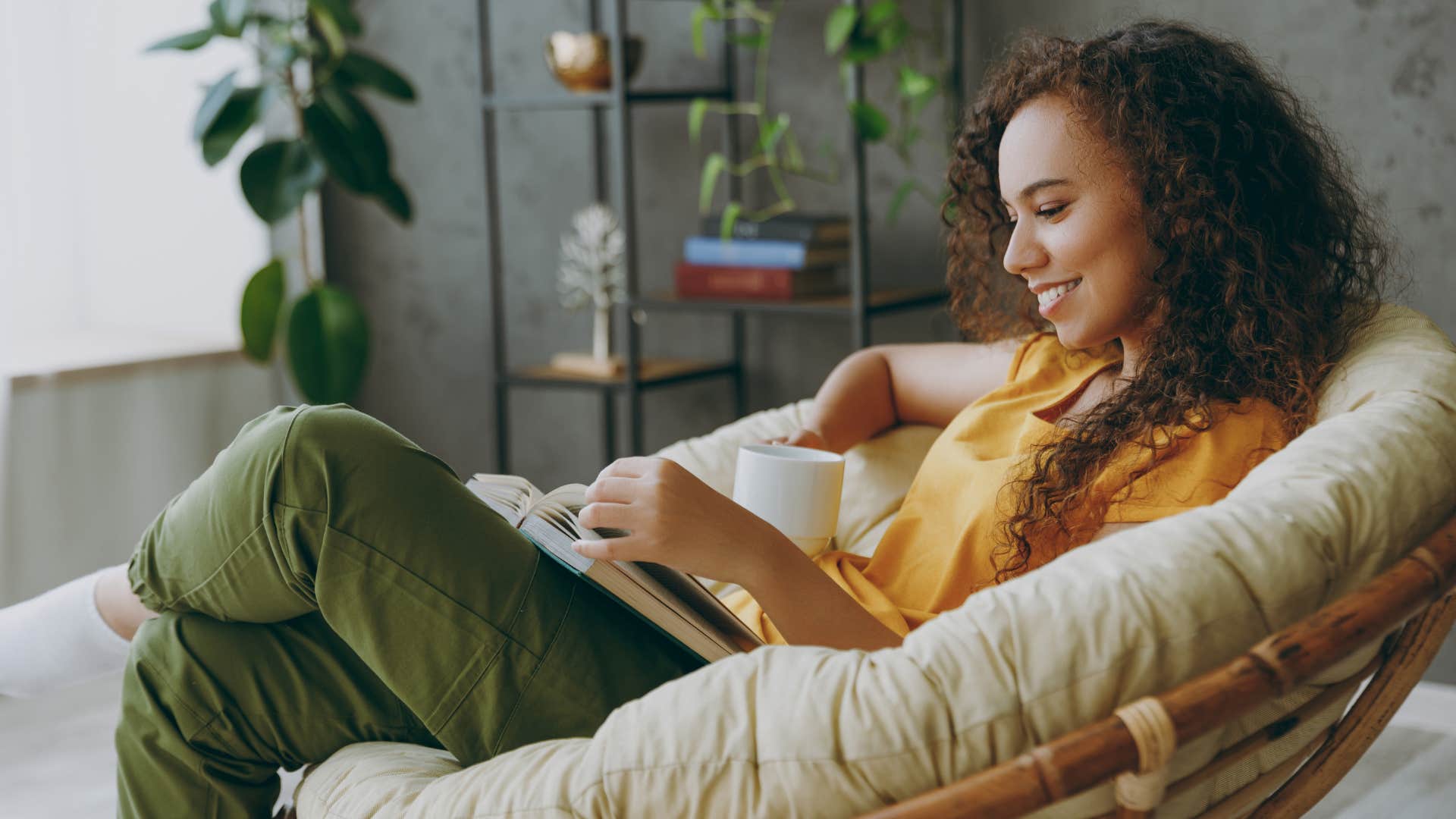 woman in yellow deeply invested in hobbies or interests as she reads book on chair