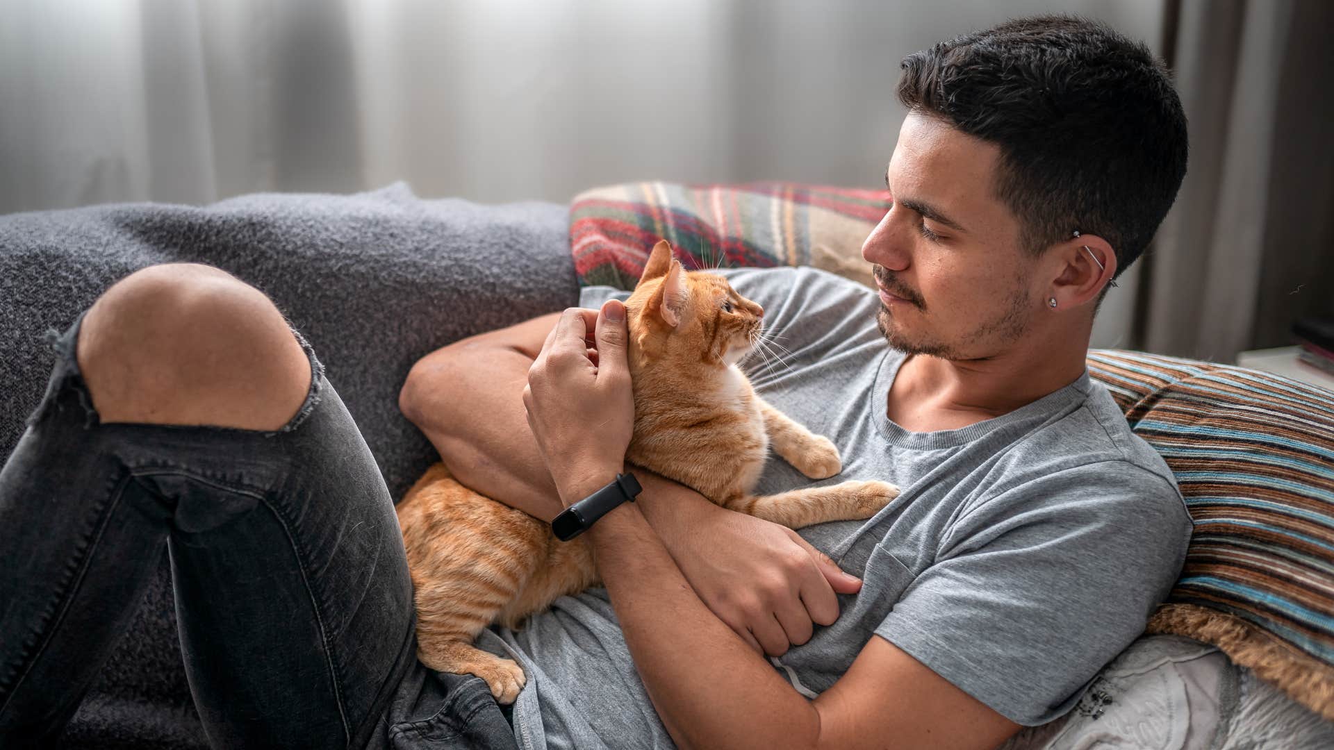 man in gray shirt preferring pets over humans as he cuddles cat