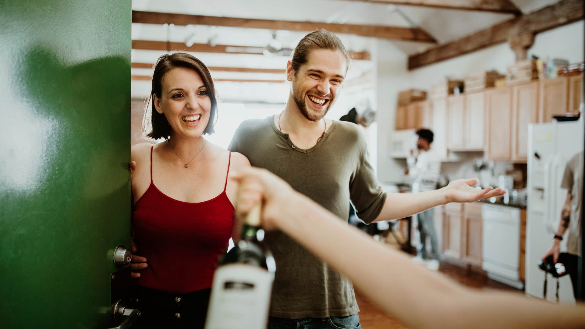 couple welcoming guests to party at their home