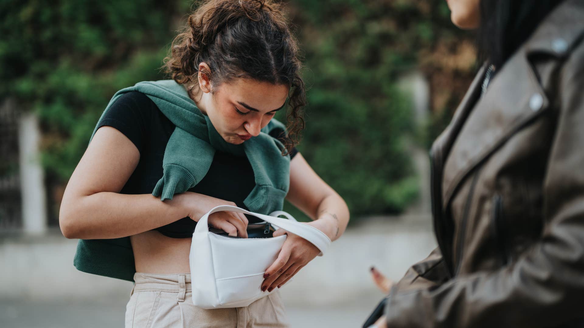 woman lending friend something from her purse