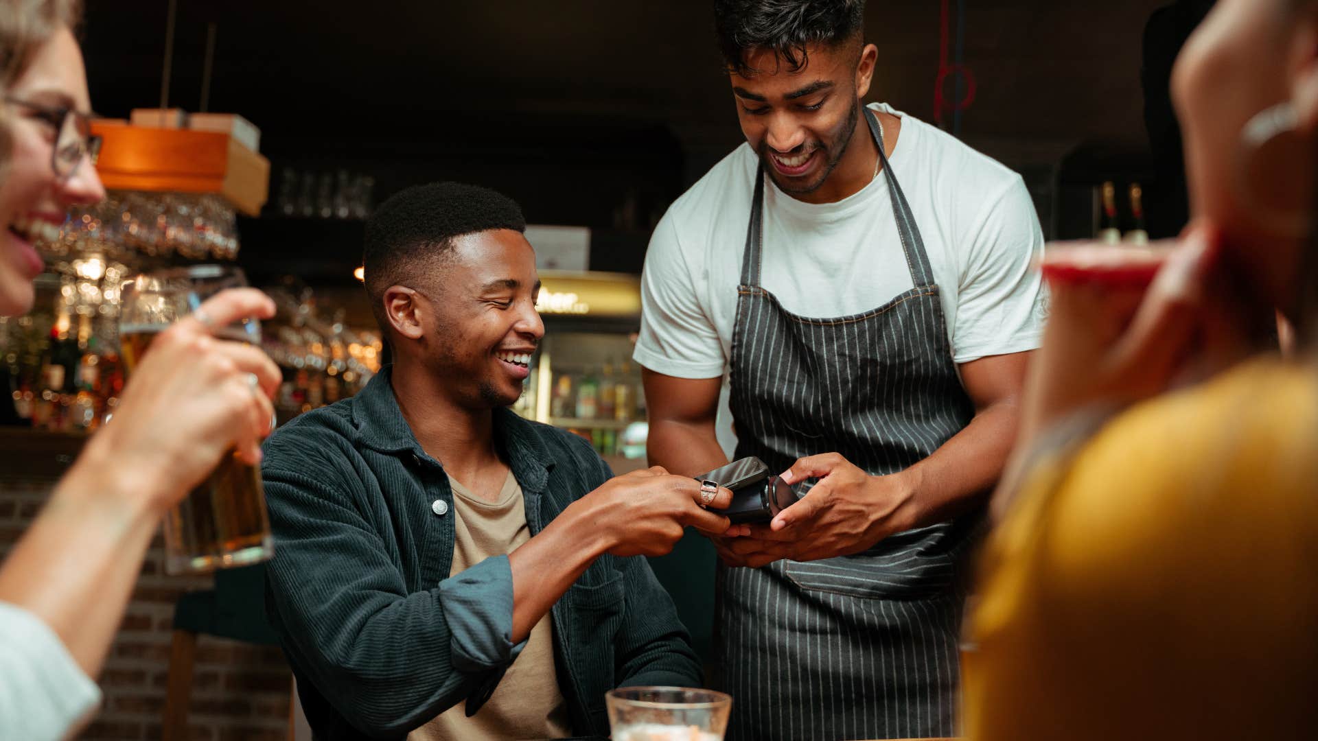 man paying the bill at dinner with friends