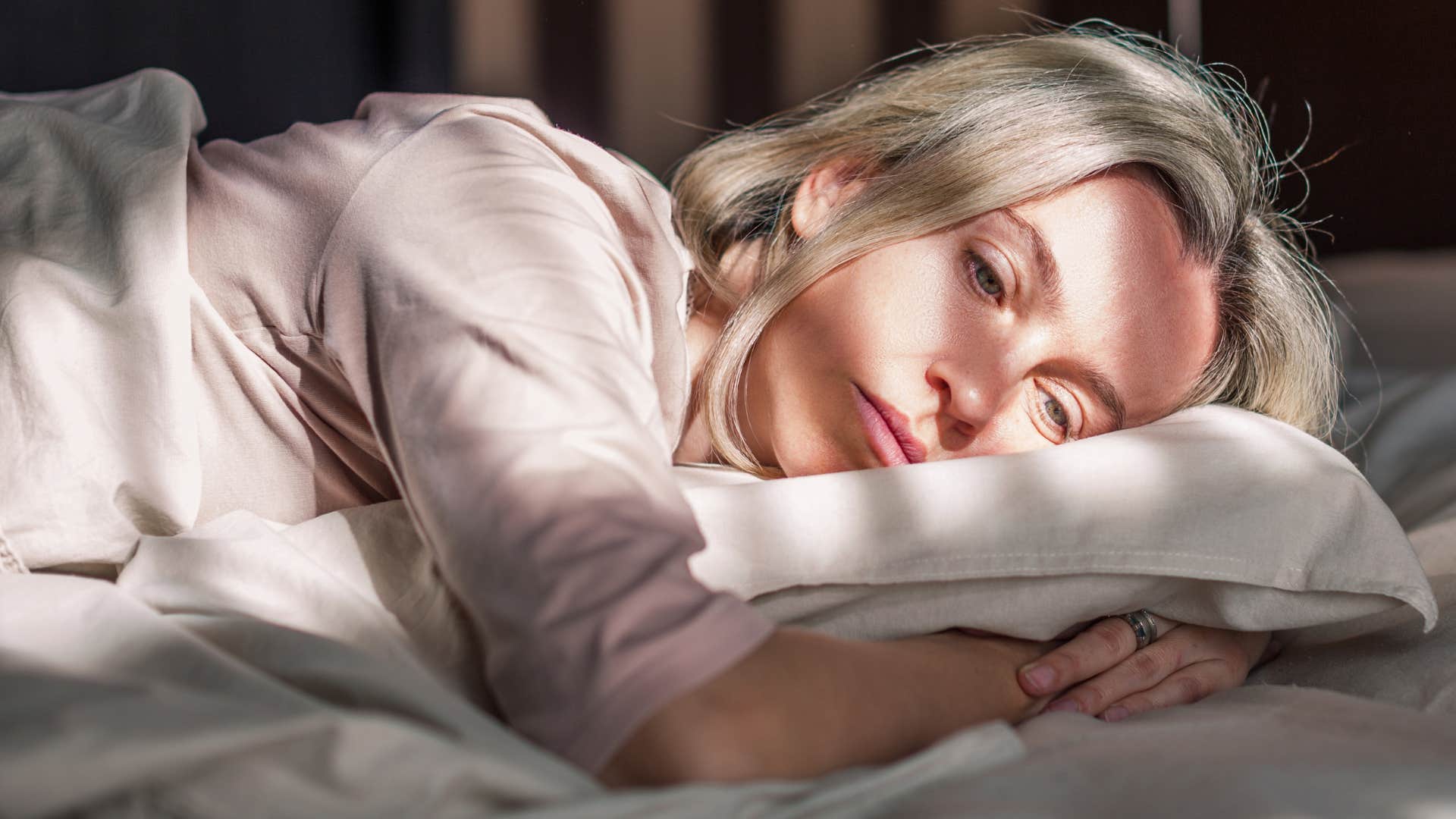 unhappy woman prioritizing sleep more than normal laying in bed