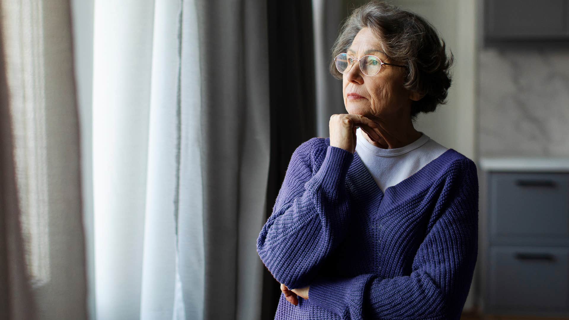 unhappy wife looking out a window spending more time alone