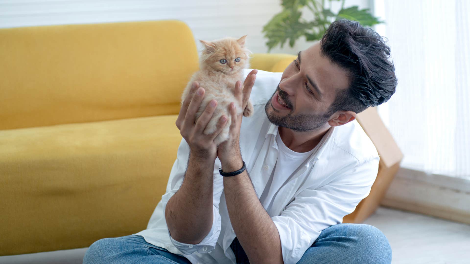 happy man showing compassion to animals holding a kitten