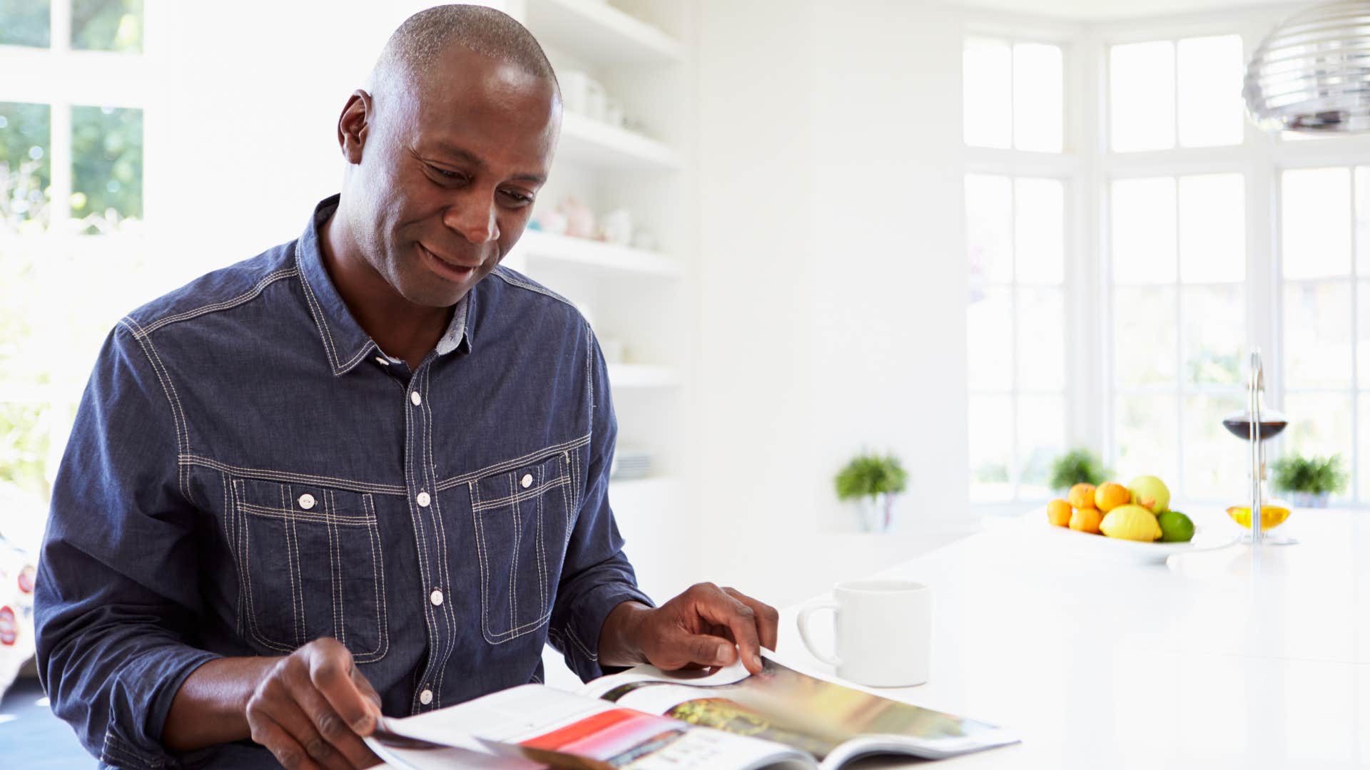 Man clipping paper coupons in a magazine.
