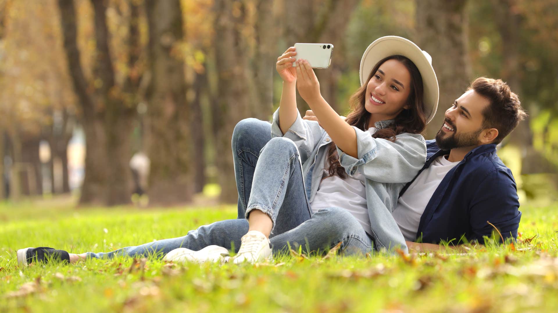 couple laying on grass smiling while taking a couple photo