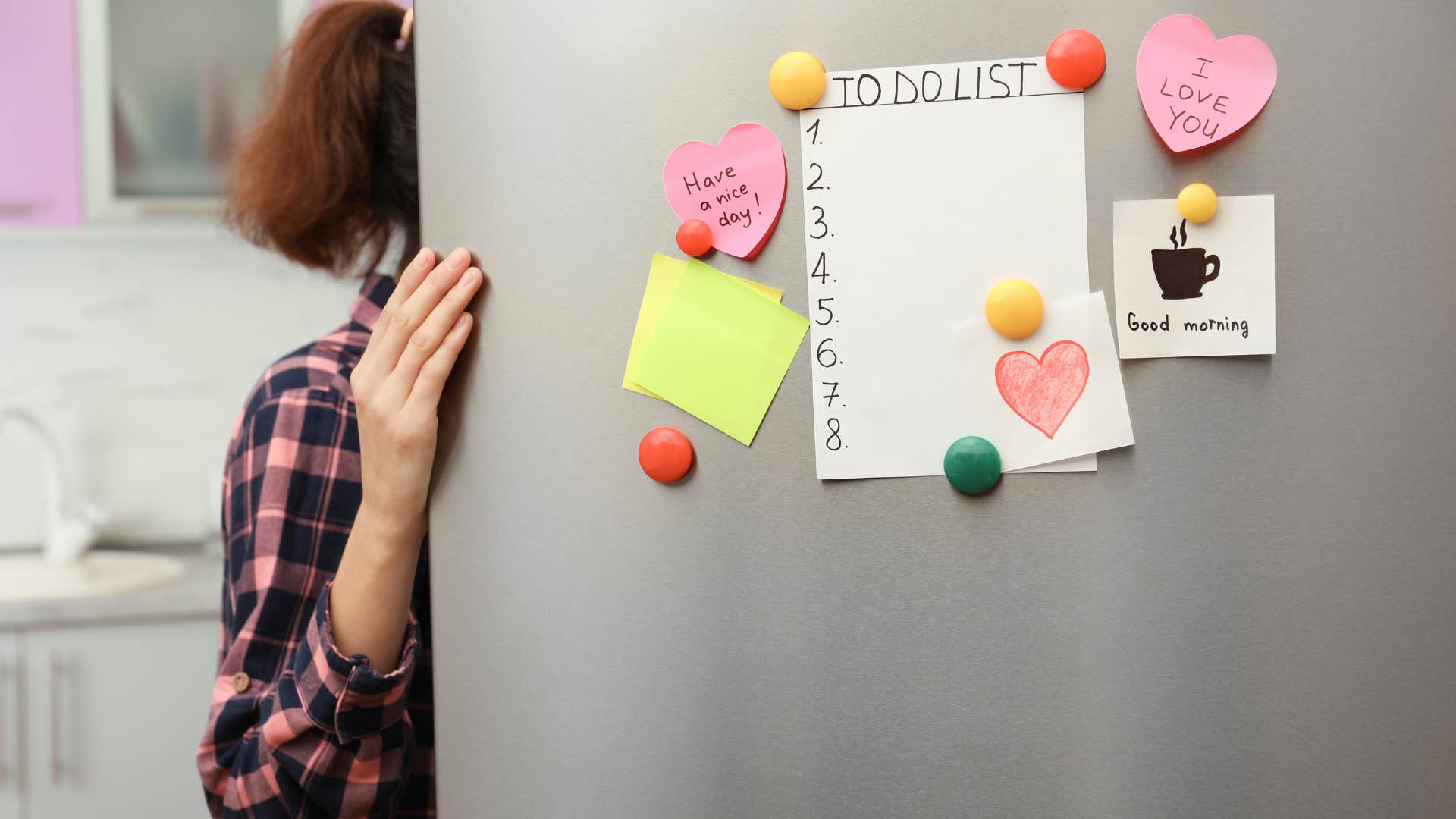 woman in plaid shirt opening fridge door as their are fridge notes on it