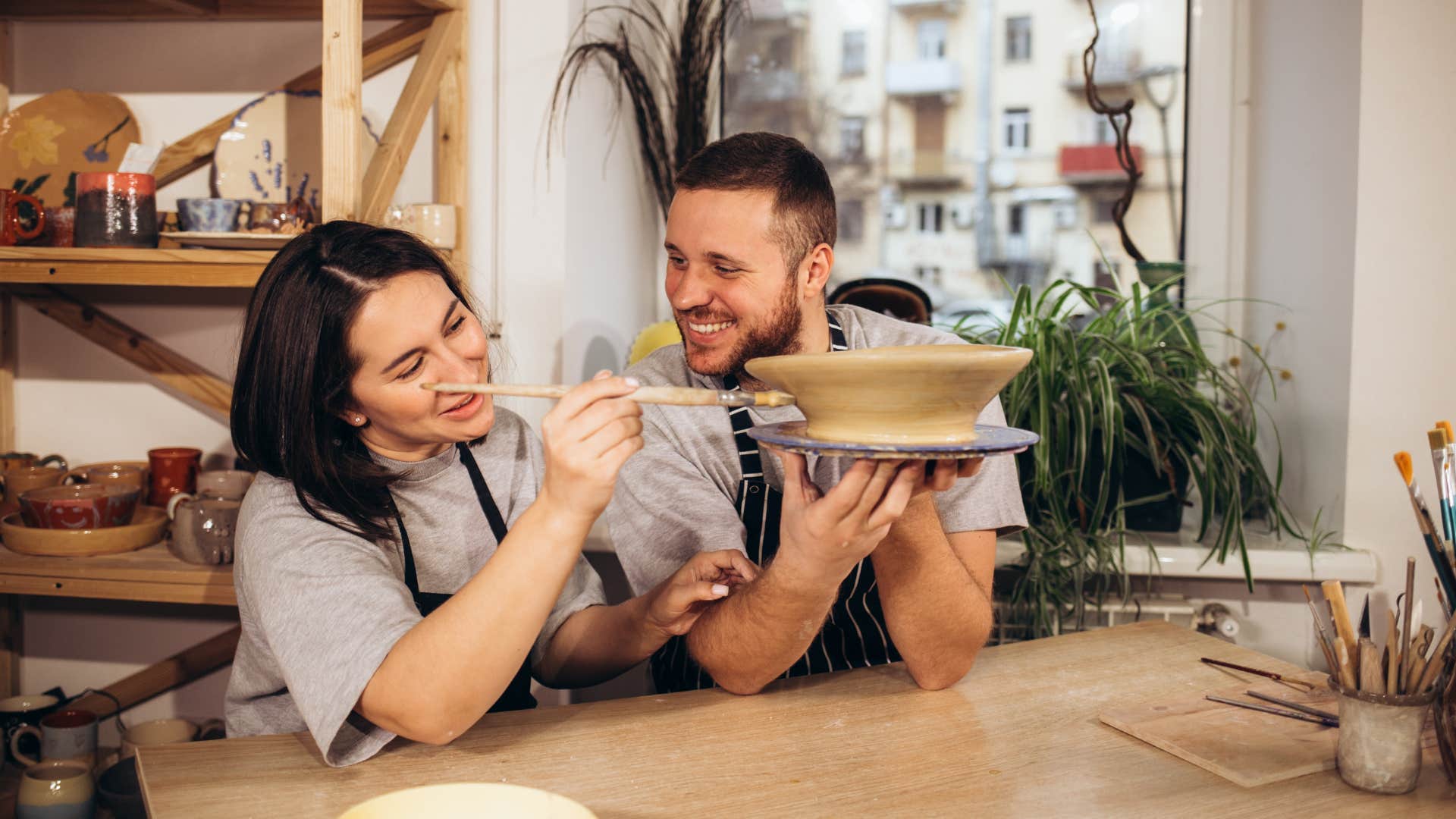 couple doing a random pottery hobby side by side while smiling