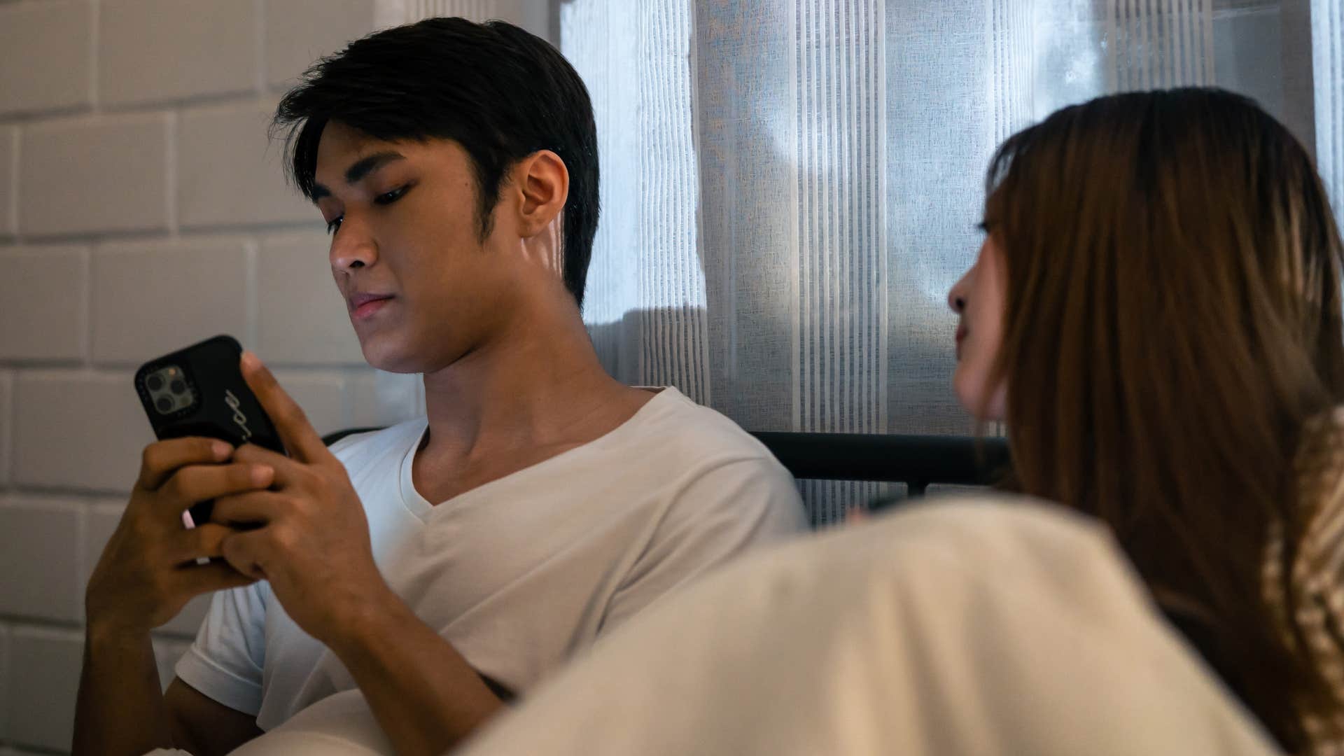 secretive man turning his phone away from his wife