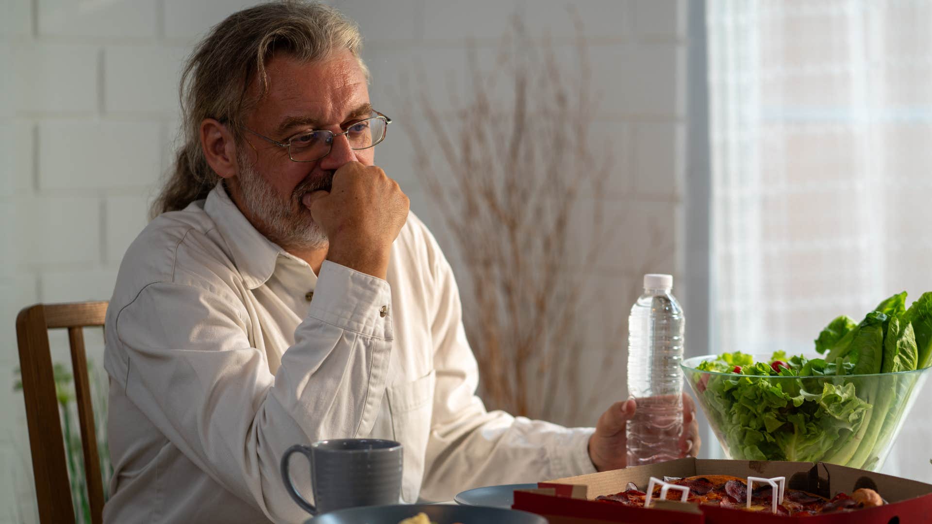 upset man eating in another room away from wife