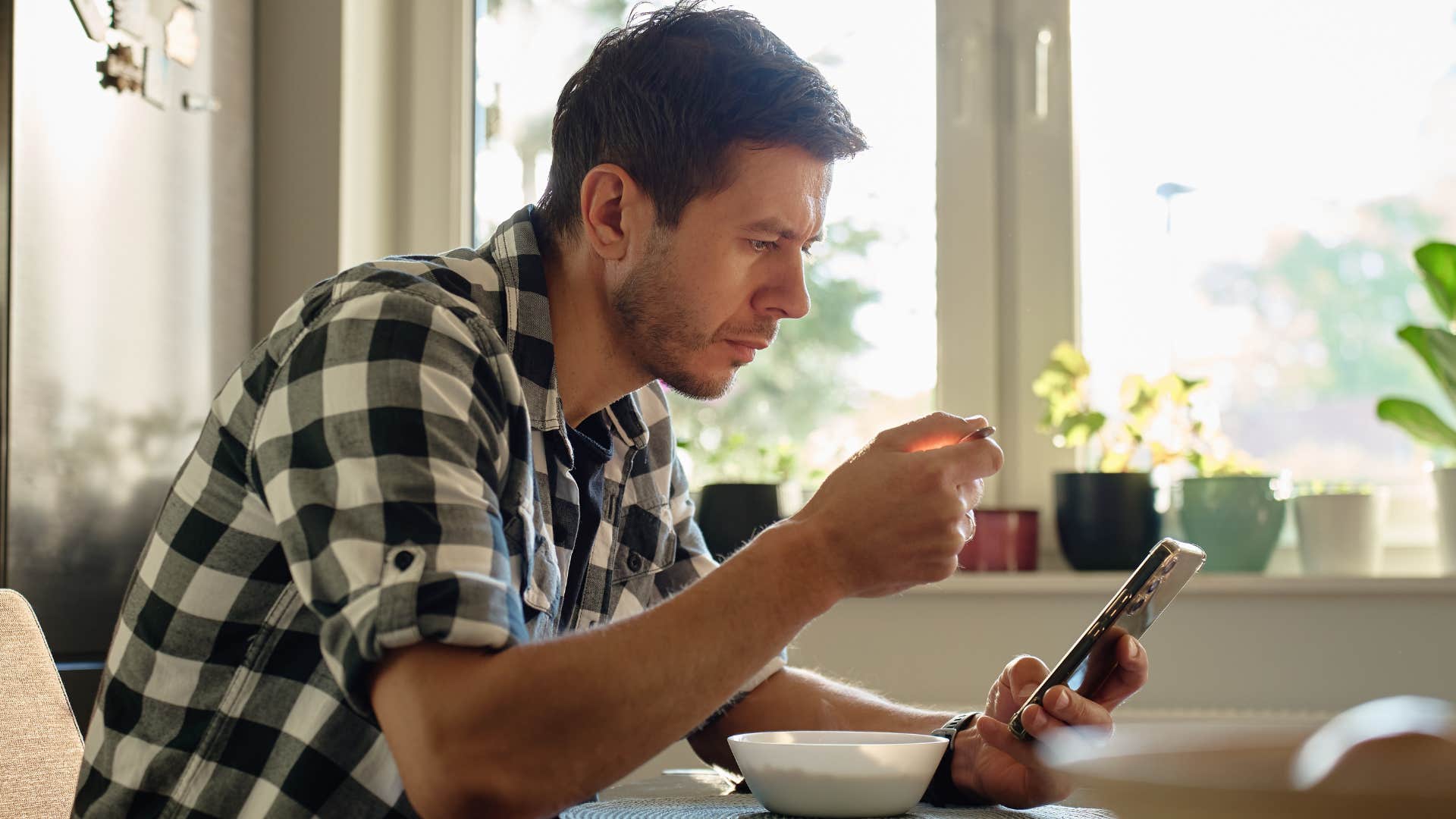 man scrolling on his phone eating meal