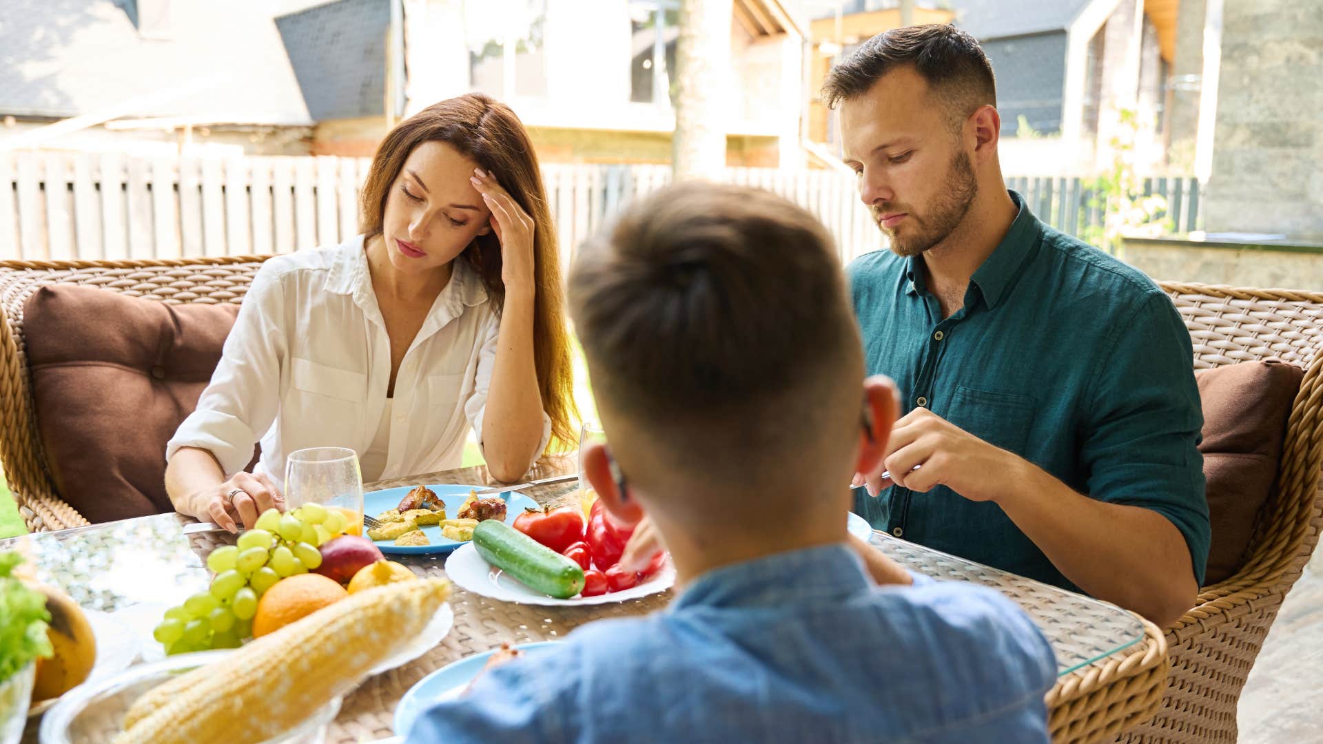 man sitting far away from wife eating dinner