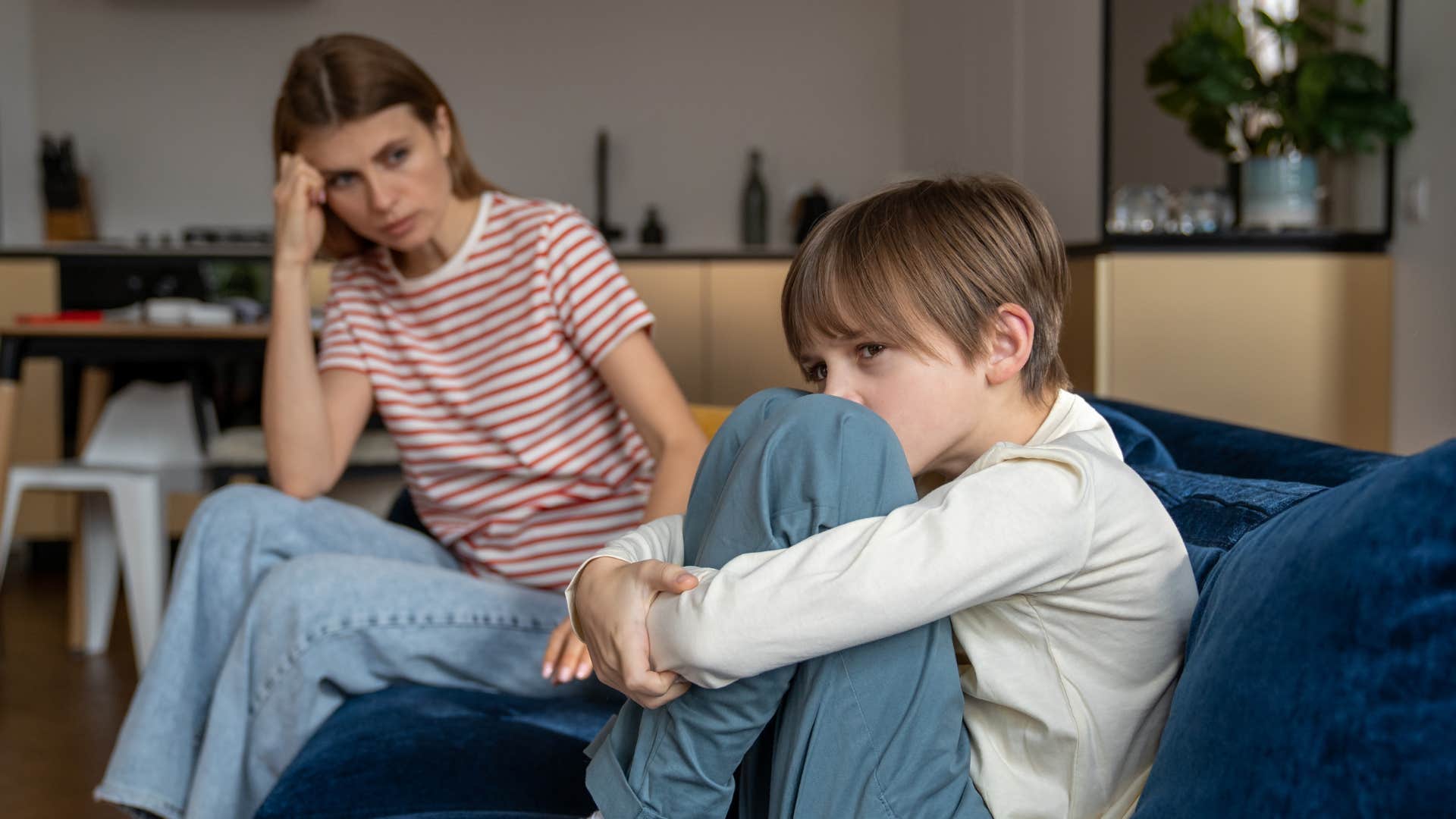 little boy ignoring mom trying to talk to him on couch
