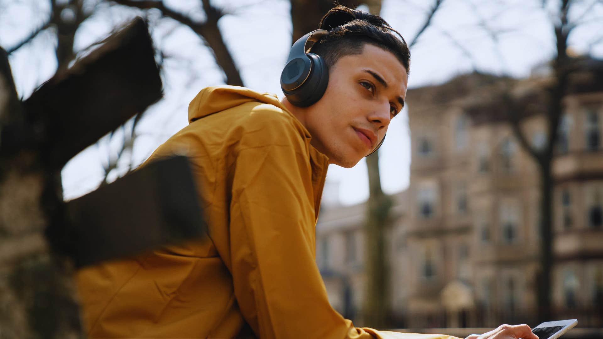 teenage boy sitting outside on bench listening to music