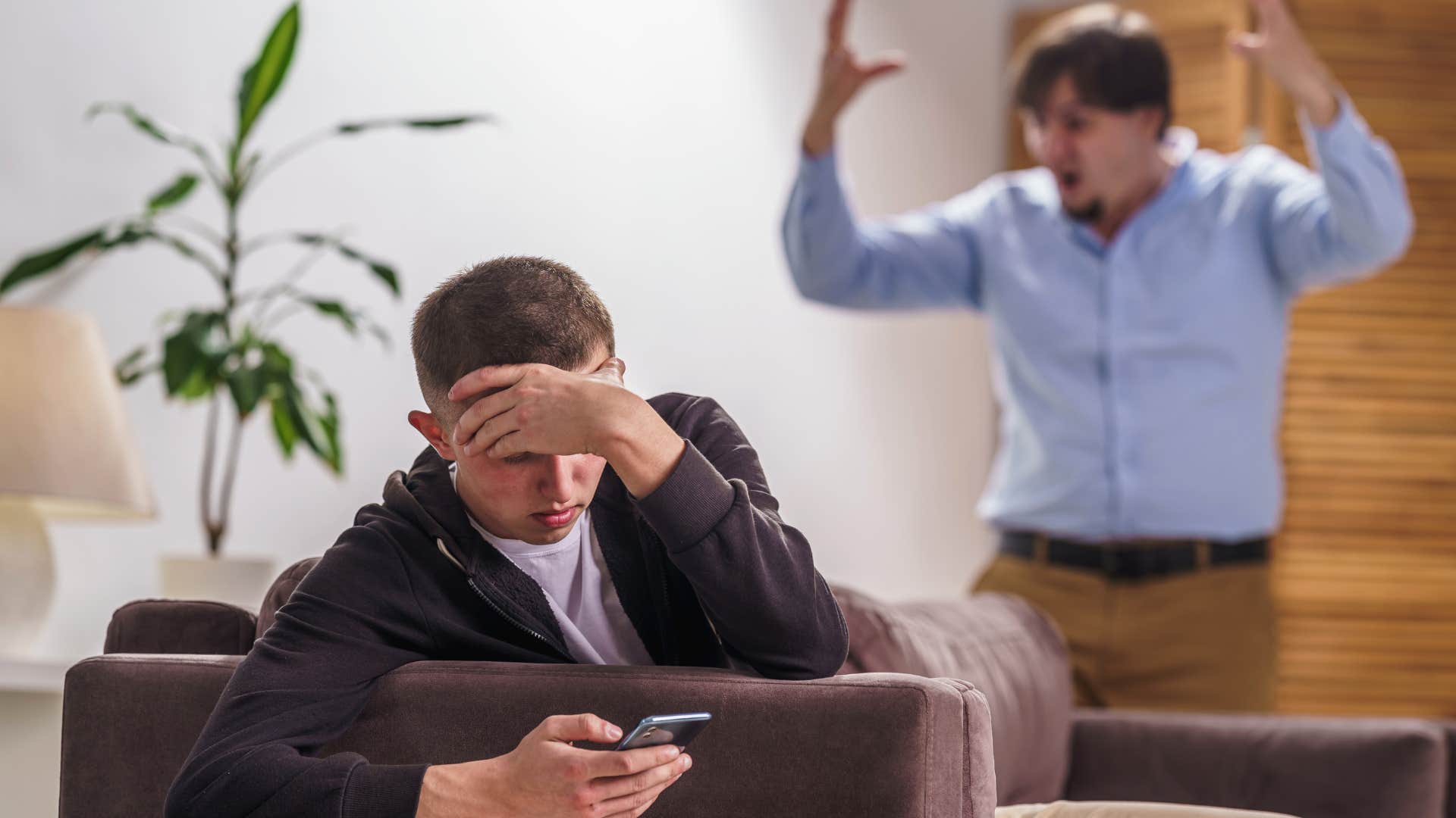 teen boy hiding away in his room away from upset parent