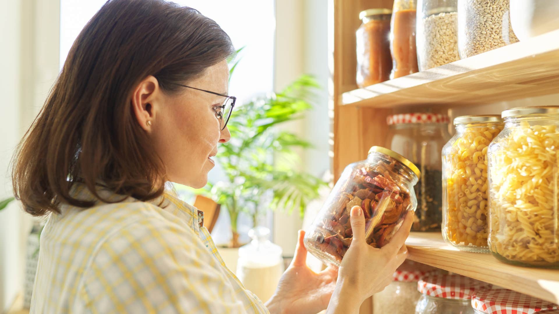 frugal woman looking at reused containers in her pantry