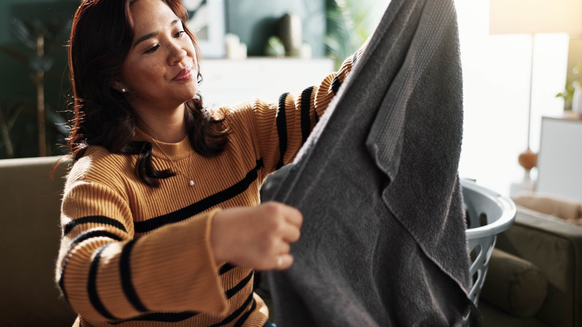 frugal woman taking worn bath towels out of dryer