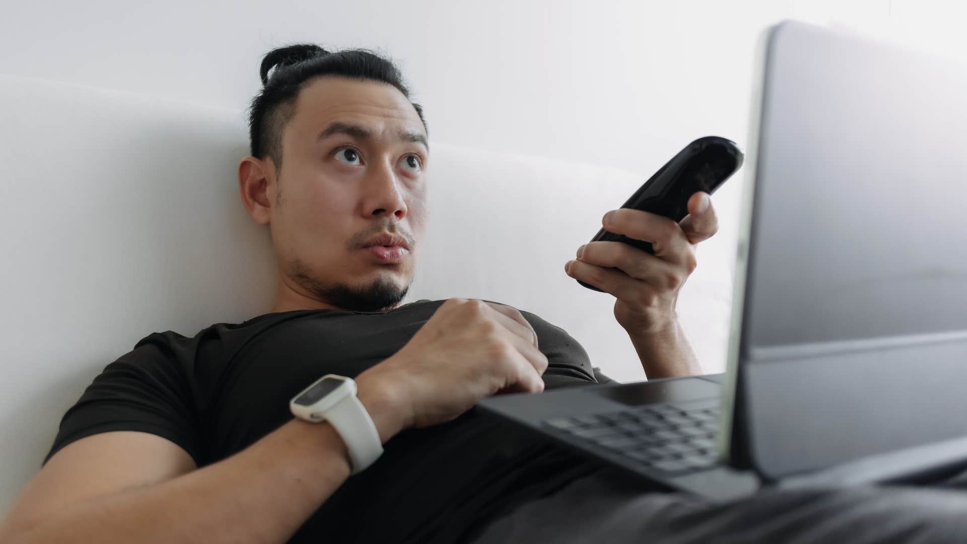 man surrounded by distractions watching television