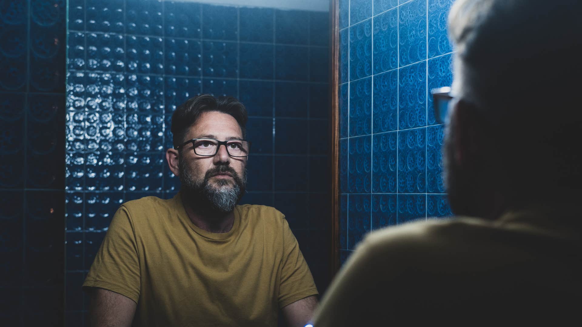 sad man looking in mirror in bathroom missing hygiene products