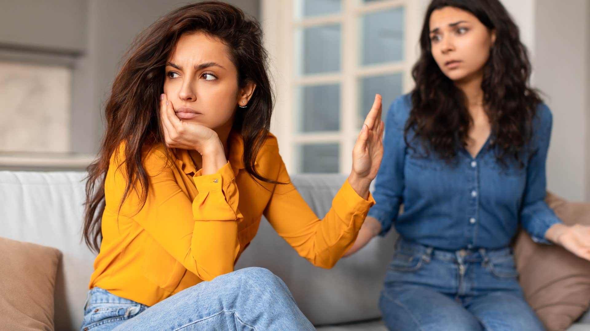 entitled woman blaming her friend holding her hand up 