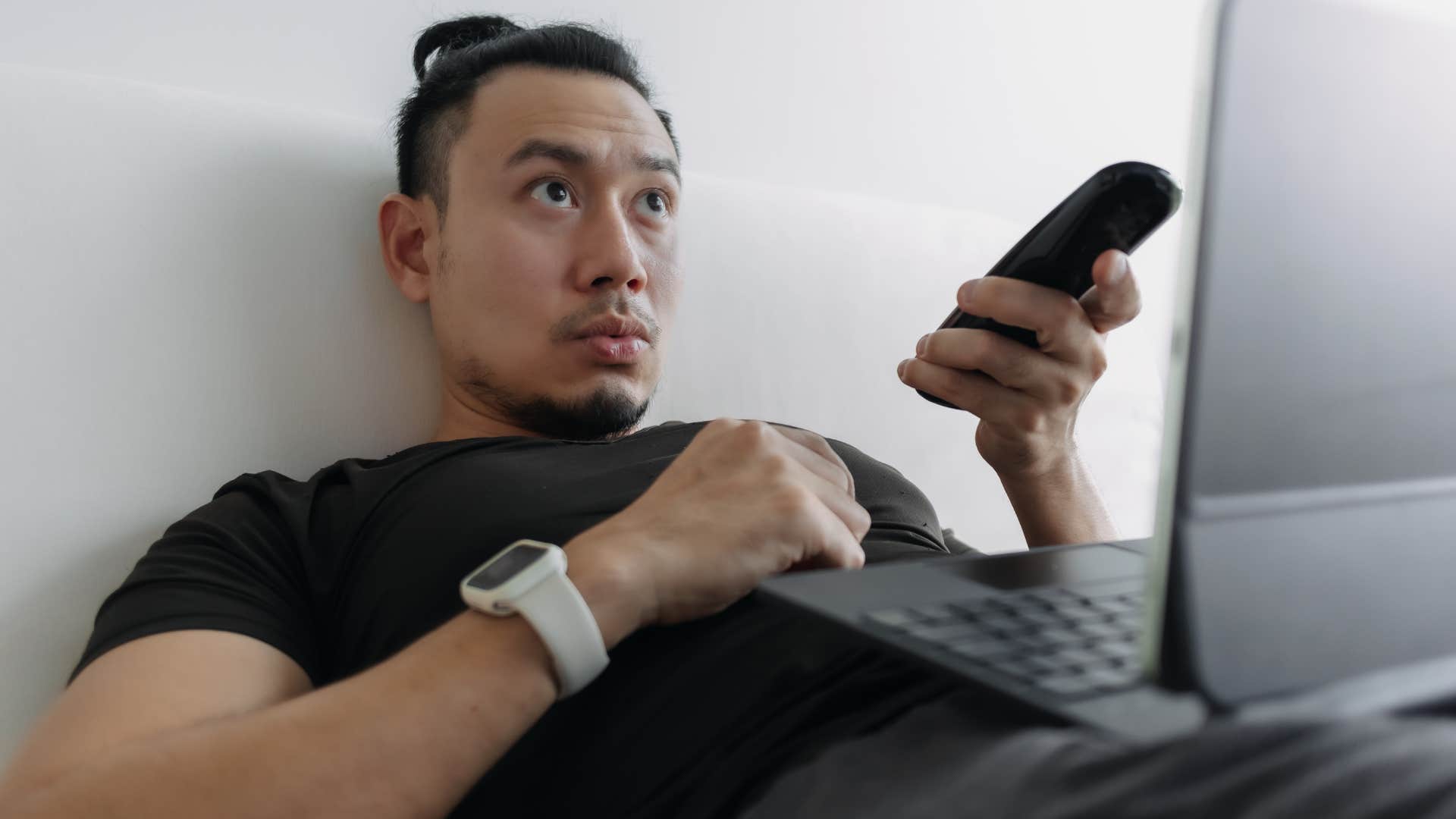 Man looking at his laptop surrounded by constant noise and screens.