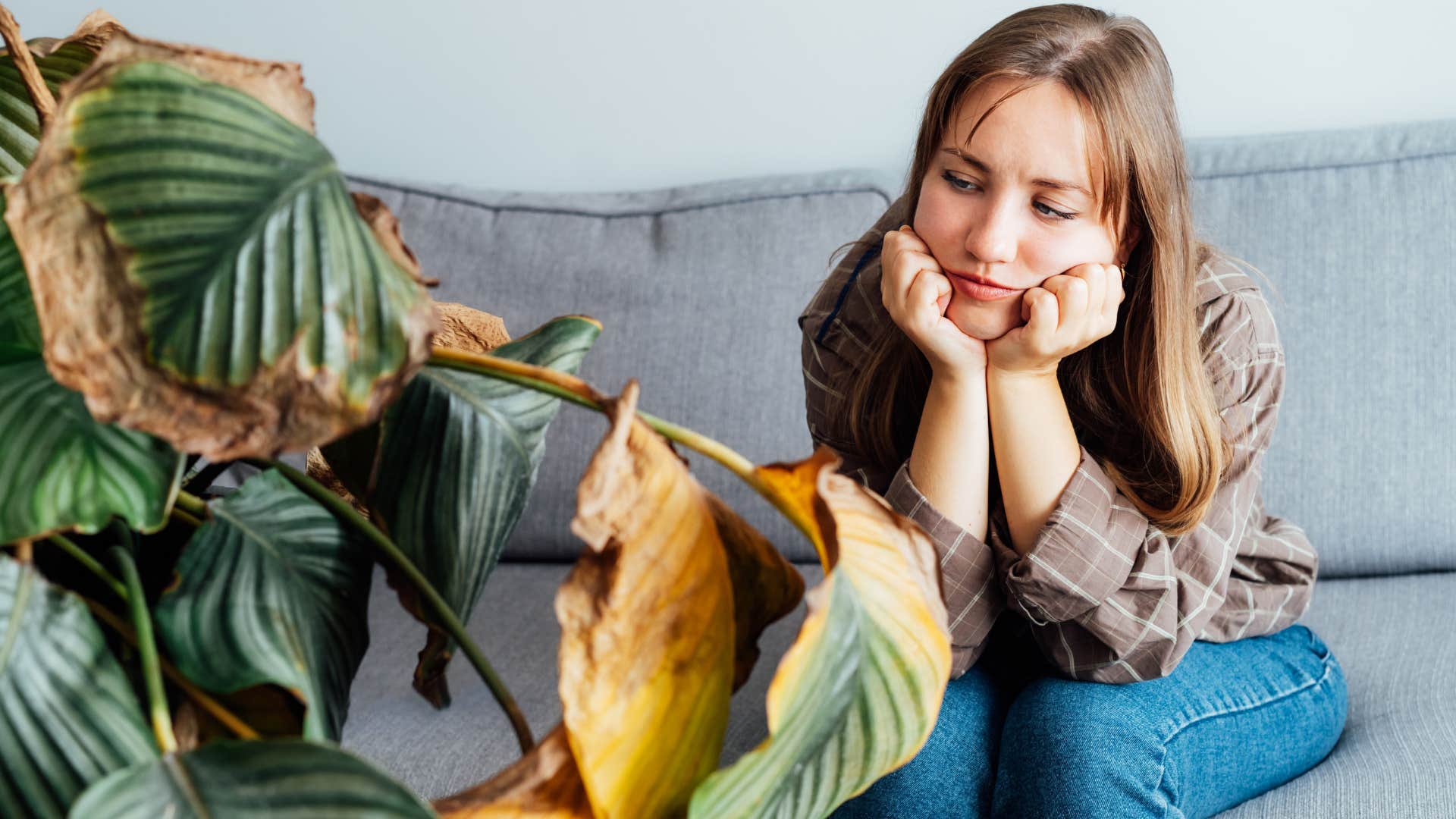 Woman looking at dead plants at home.