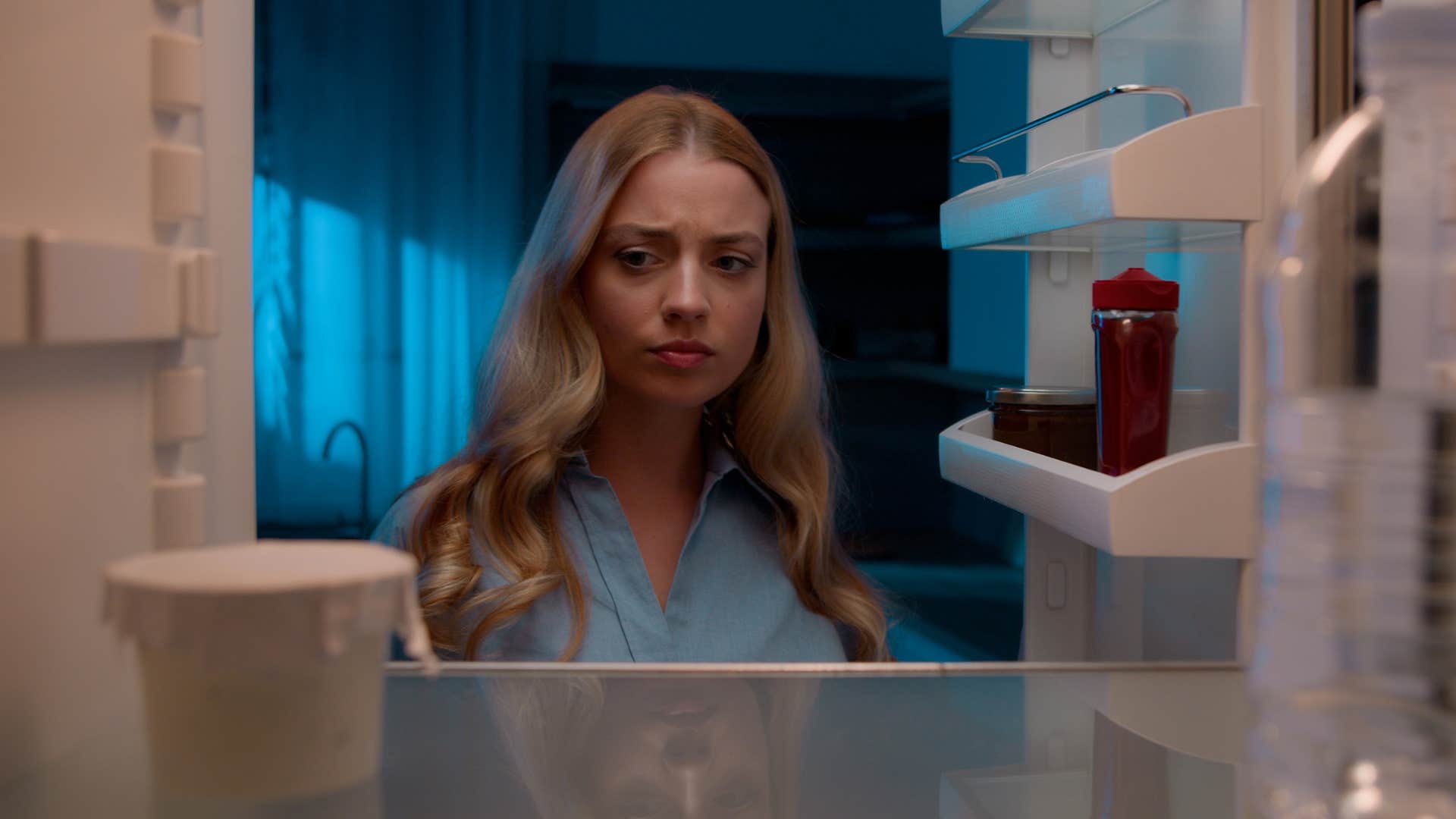 Woman looking in an empty fridge at home.