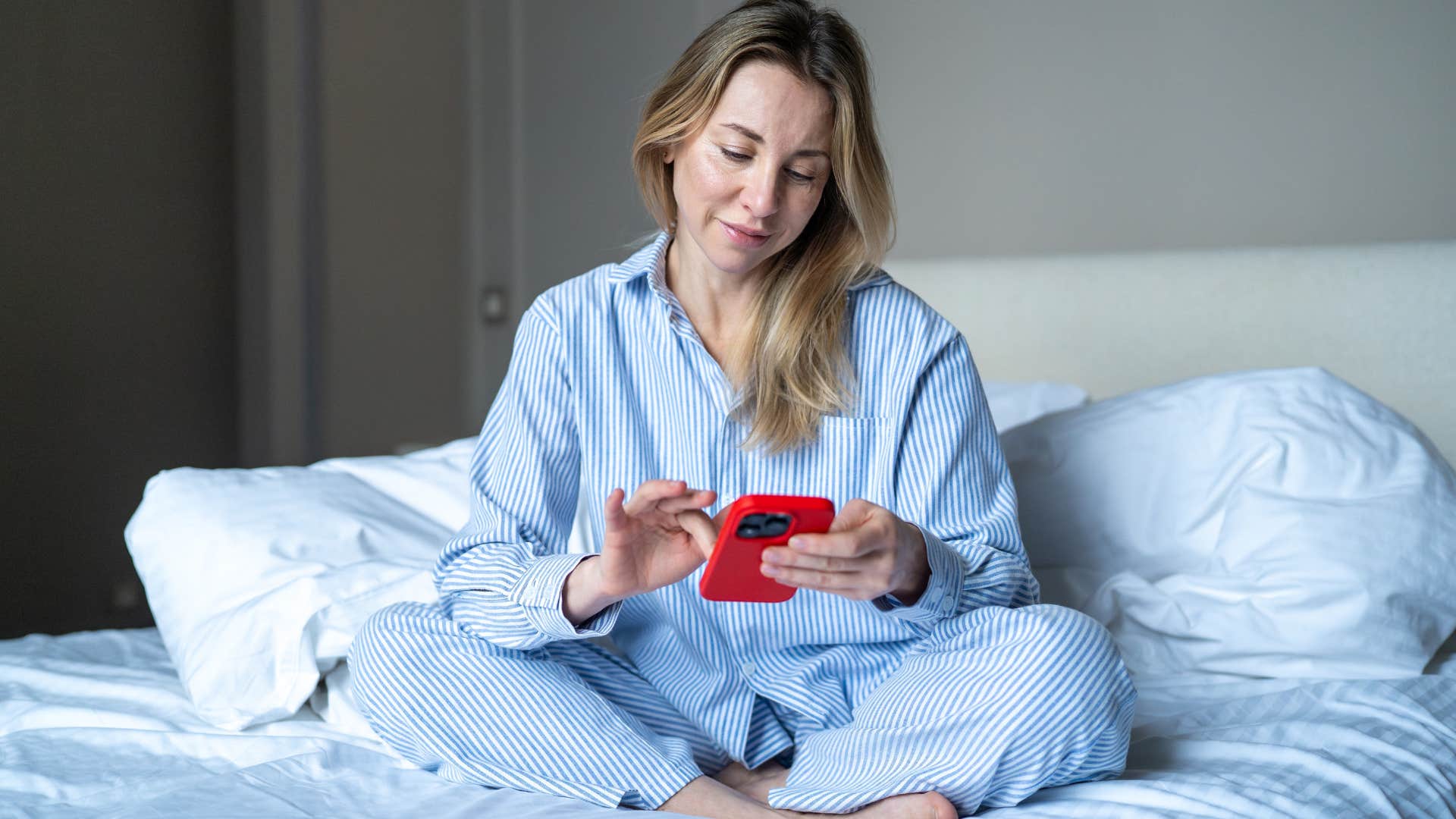 Woman sitting in her consistently unmade bed at home.