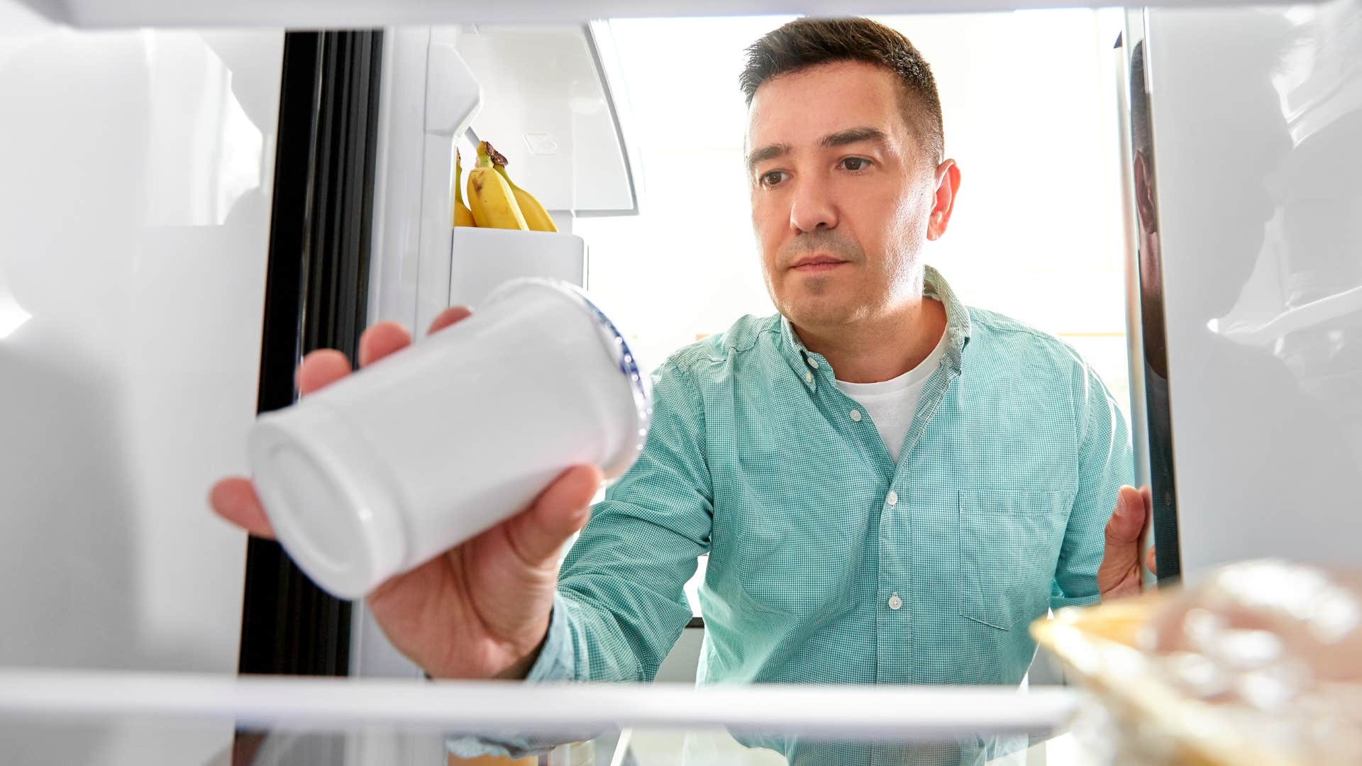 Man looking in a fridge that only has expired food.