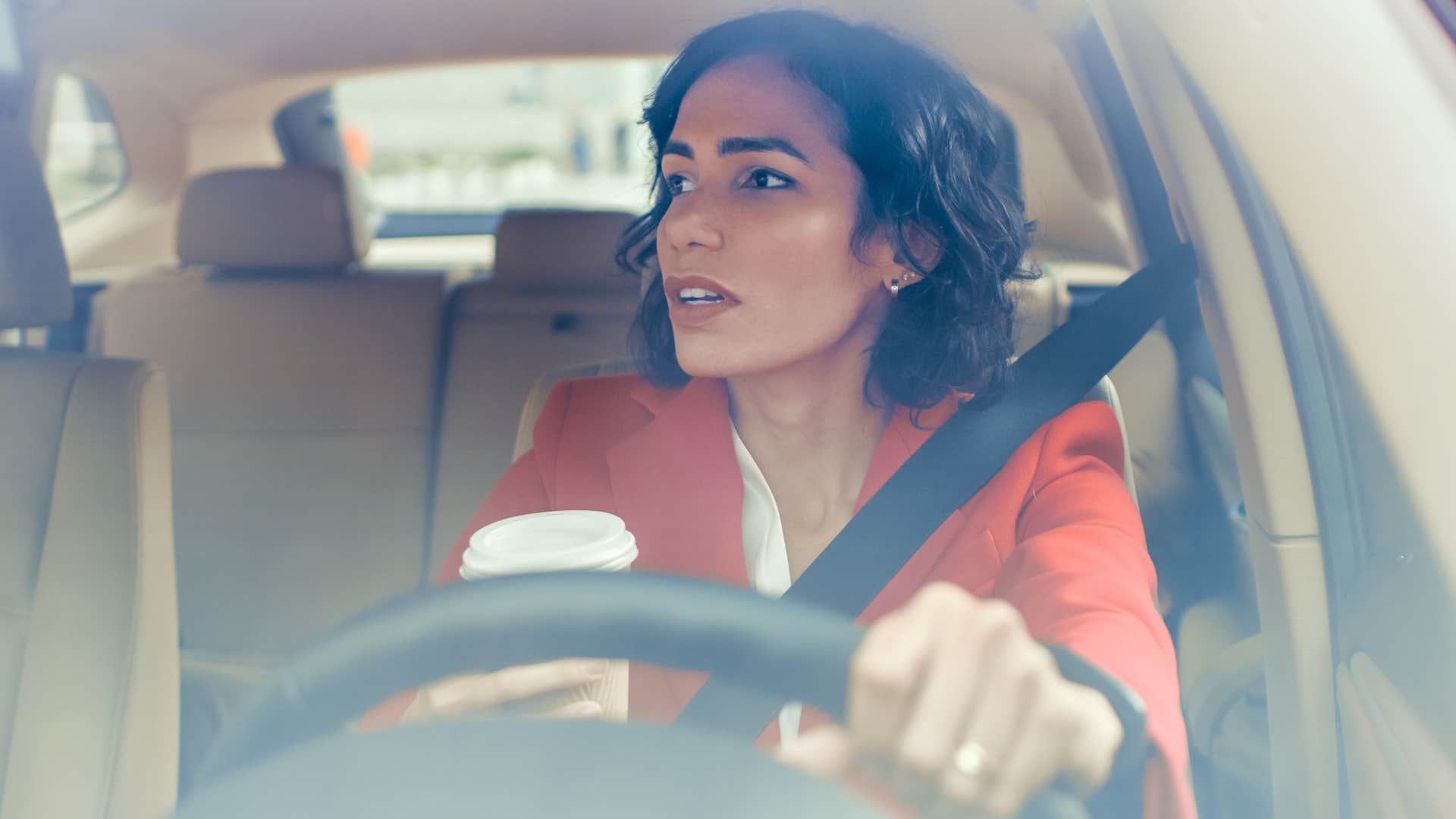 woman driving with empty coffee cups in her car