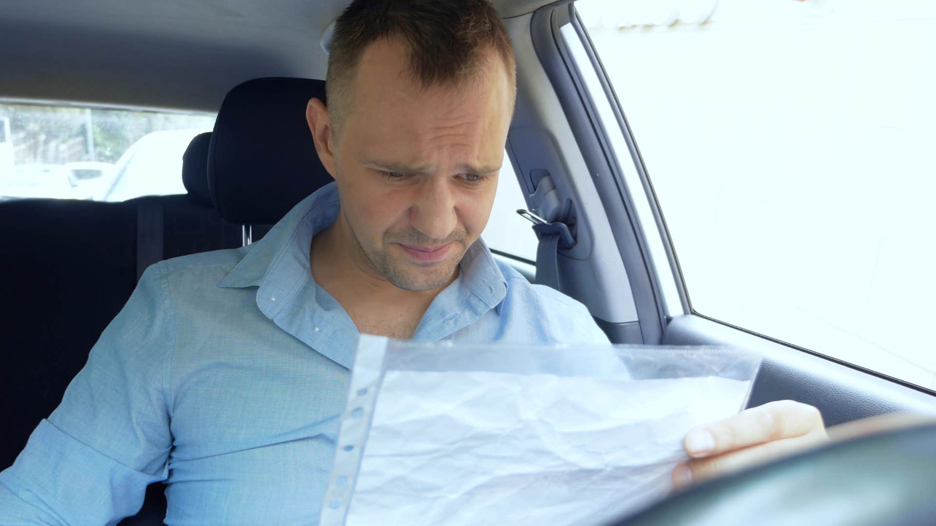 concerned man looking at wife's expired car insurance and registration papers