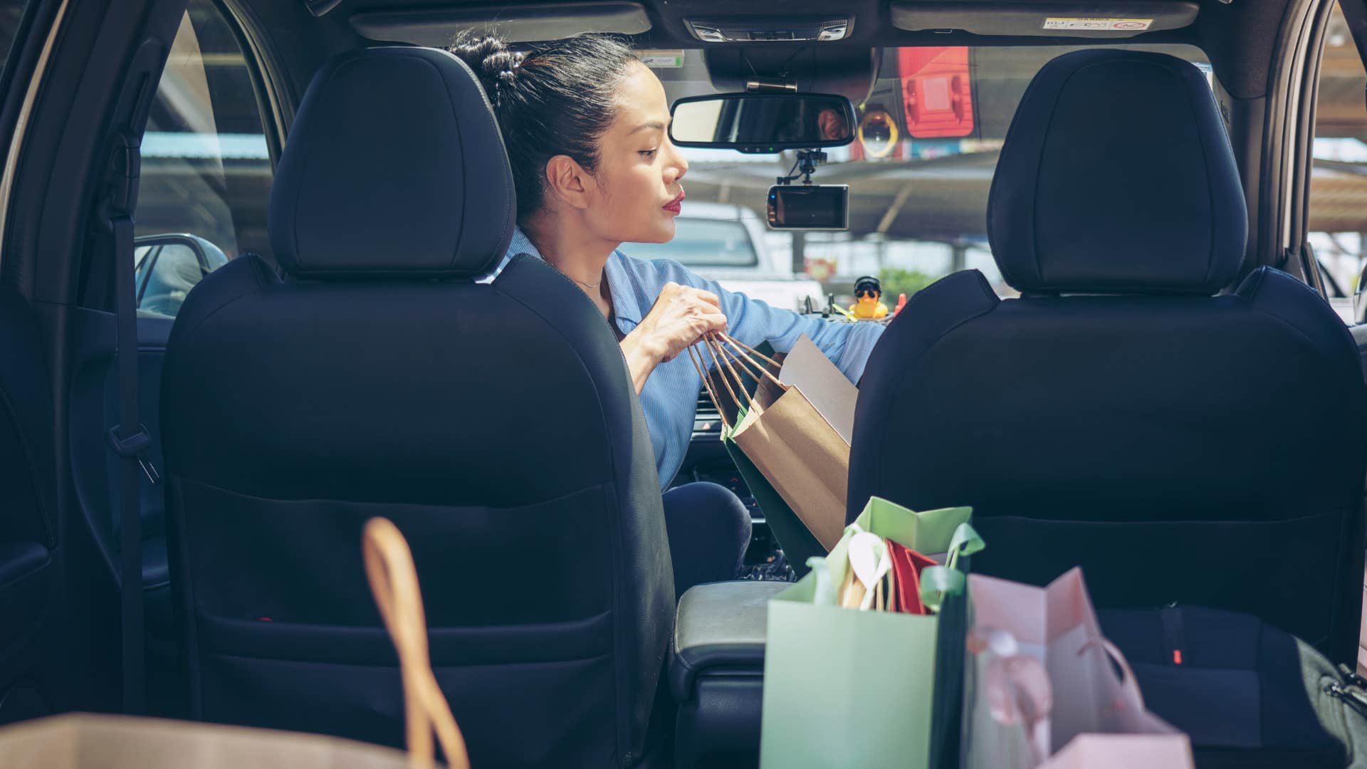 woman putting bags in her car with a full trunk