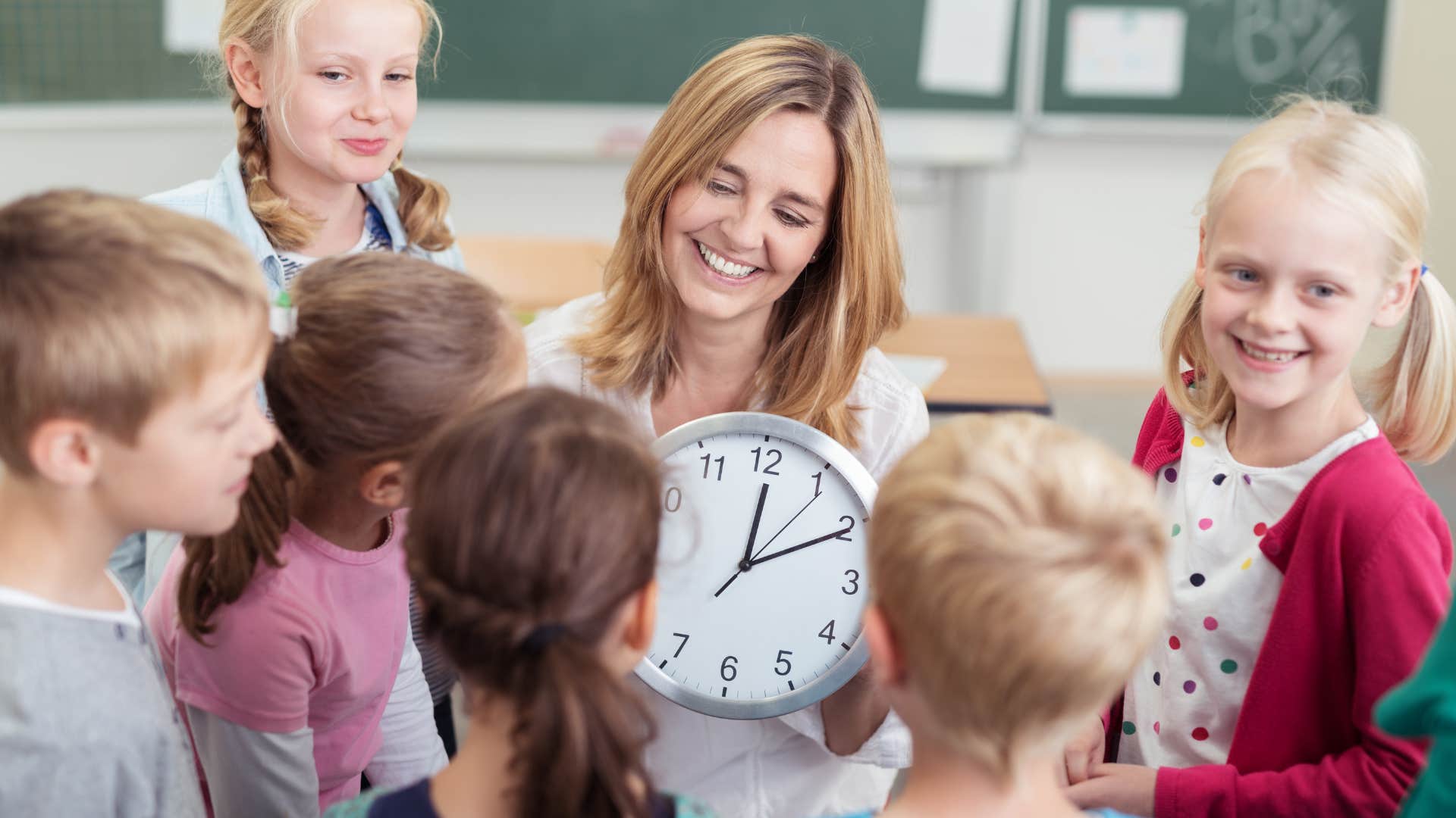 teacher showing her students an analog clock