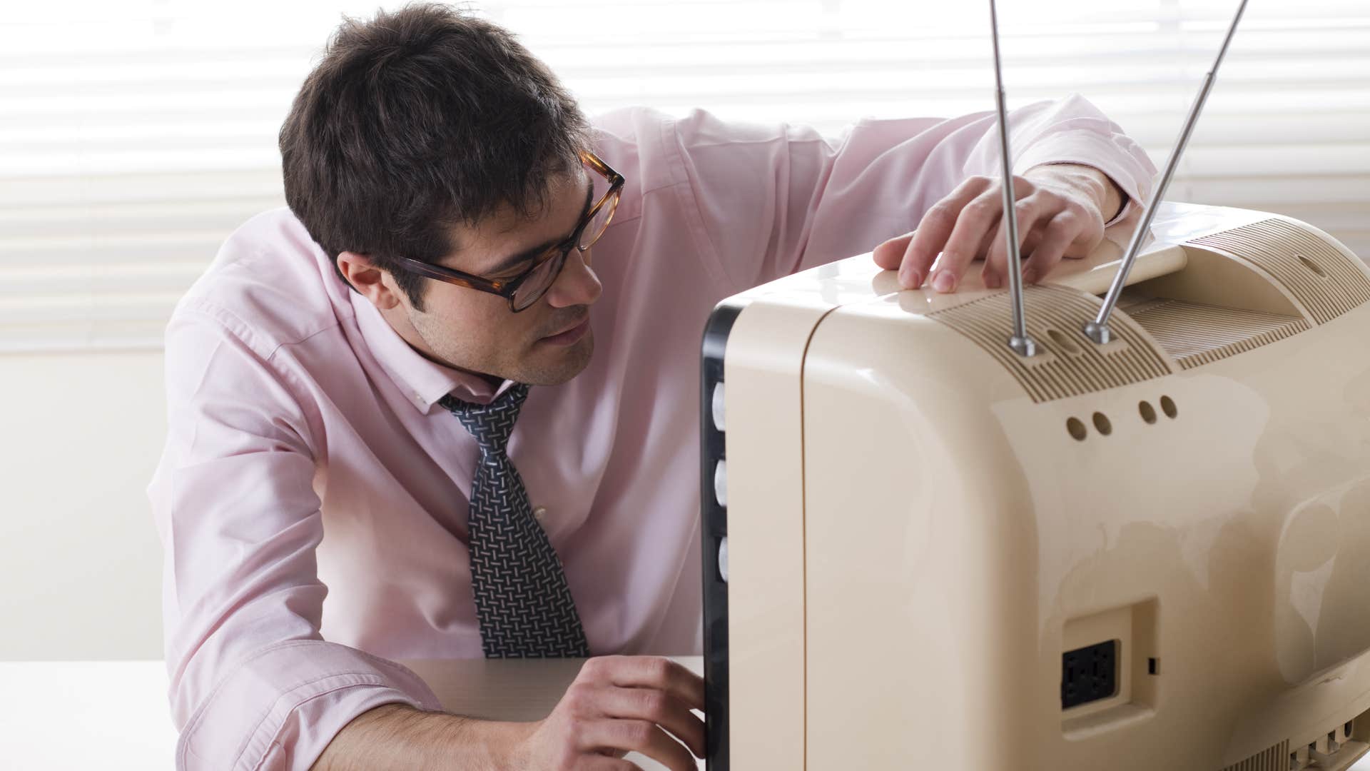 man changing the channels on old tv manually