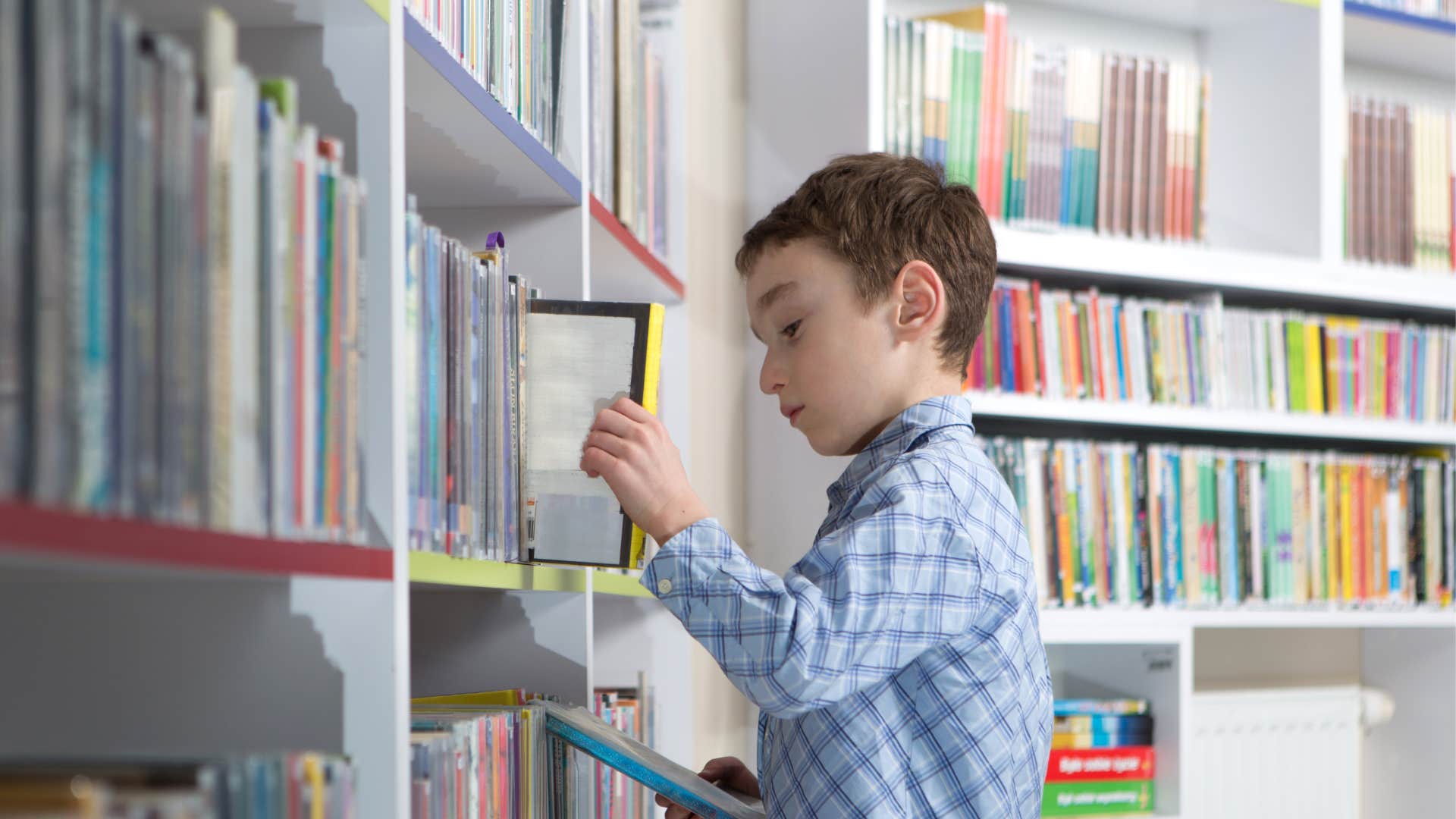 young boy at the library looking at books