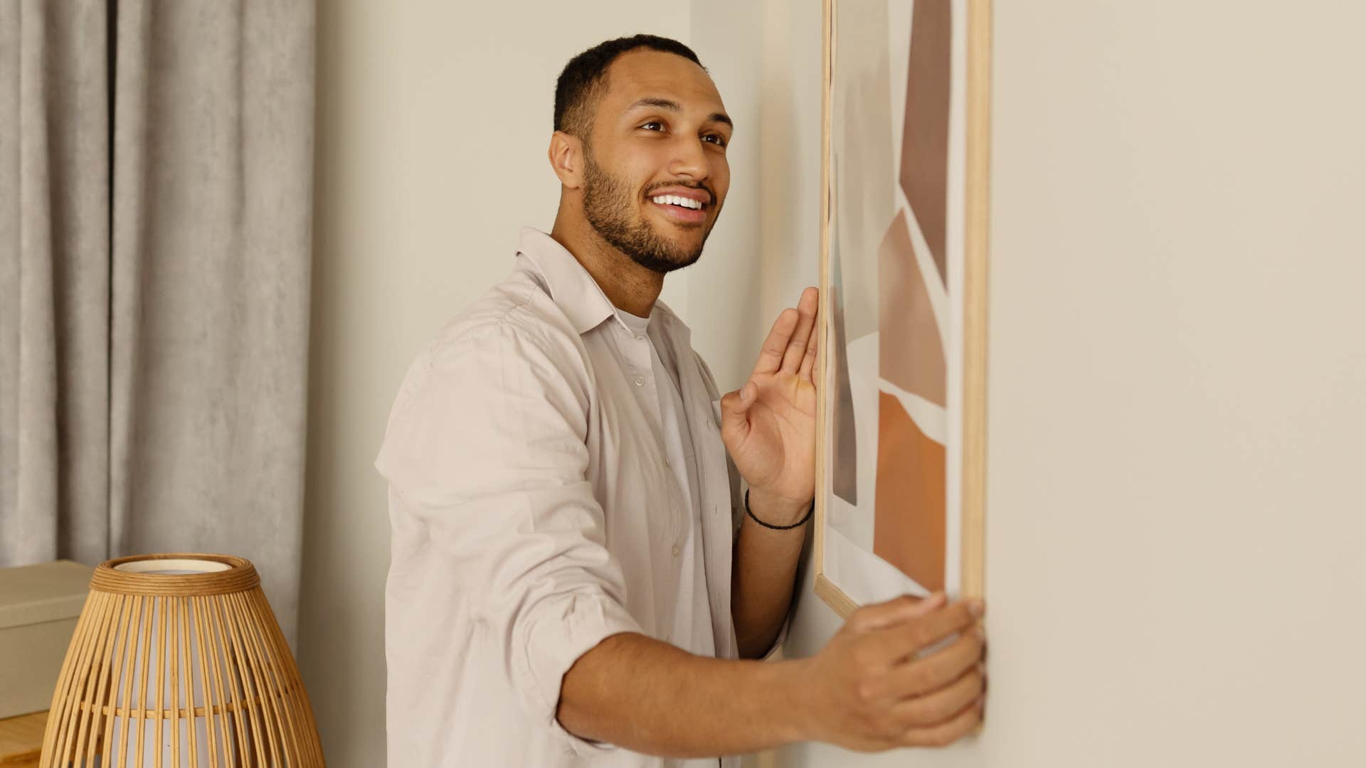 Man hanging artwork at home.