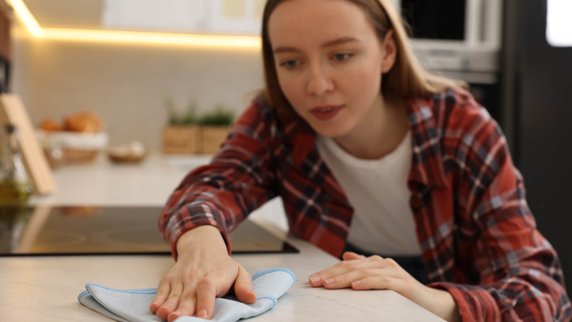 Woman wiping down her marble countertops at home.