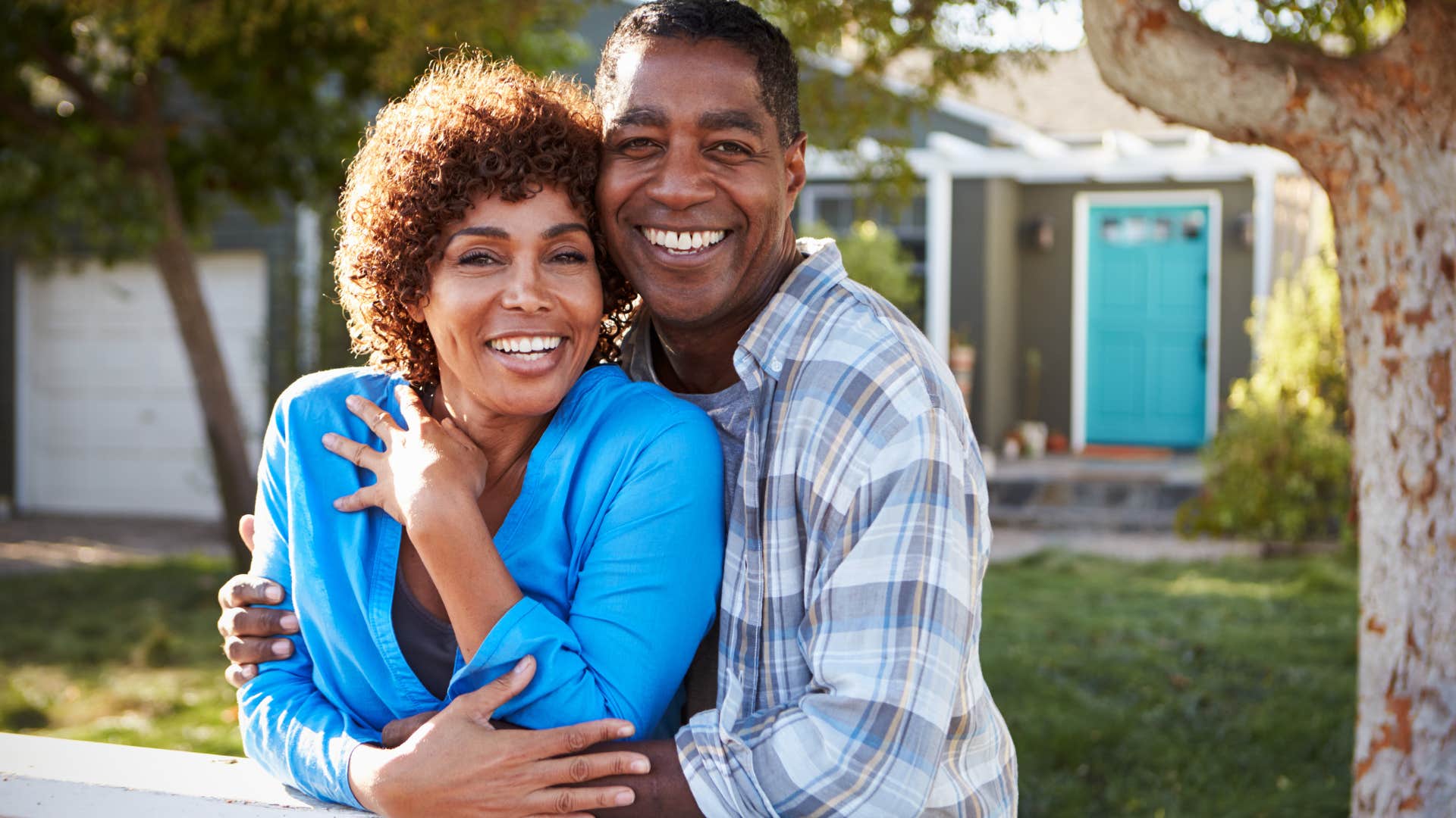 Woman sitting in a yard at home with her husband.